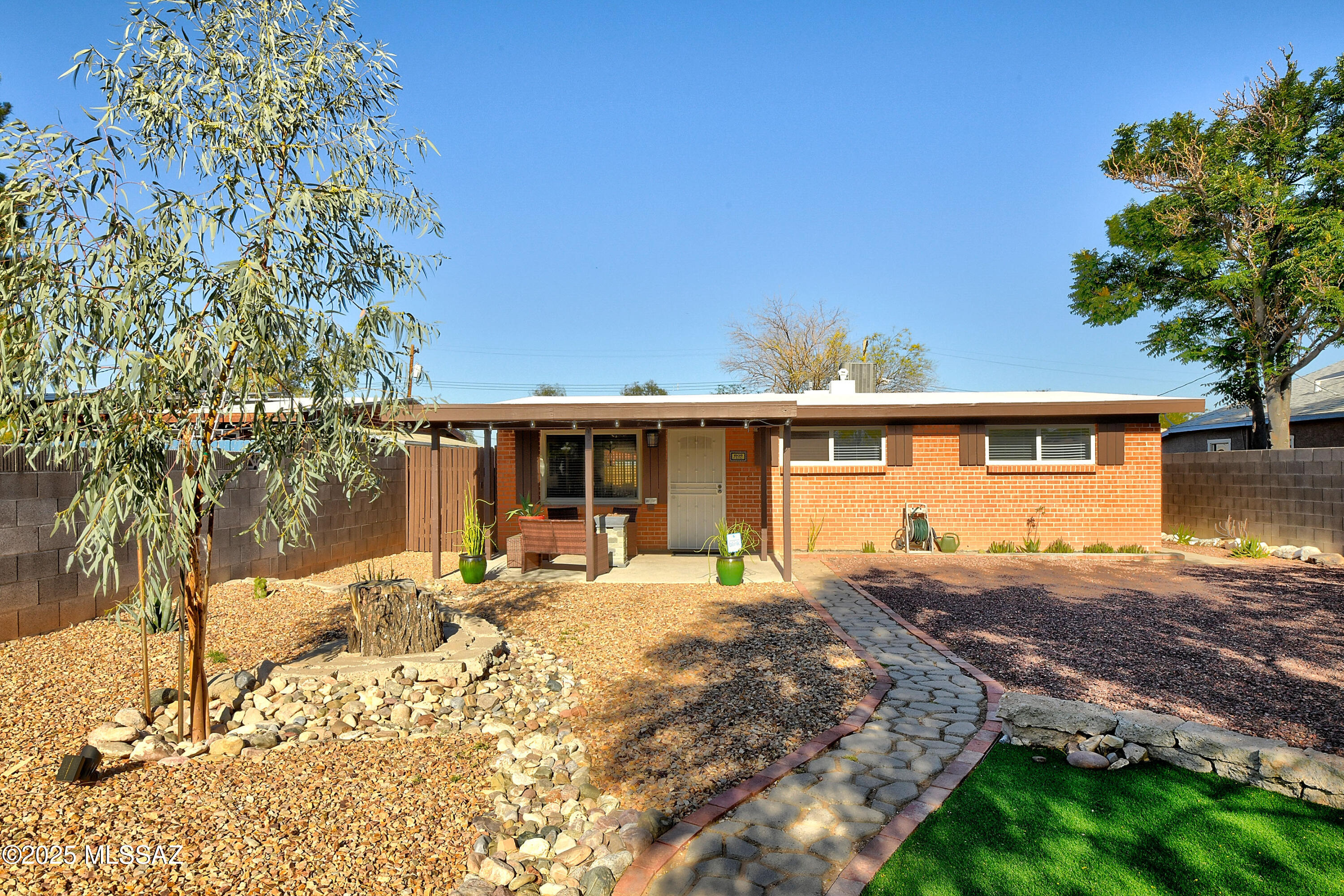 Super cute 1950s 3BR brick ranch home w/abundant charm and chic updates! Features incl vaulted ceilings, an incredible yard with covered patio, a light and bright kitchen with granite counters, peninsula and a large skylight.  Enjoy newer HVAC, water heater and electrical subpanel for peace of mind. The spacious bonus room is ideal for an art studio, gym, or extra hangout space. Relax out back on that patio that overlooks the large, low-maintenance yard with turf, perfect for entertaining or play. The front yard is equally inviting with turf and a large shade tree. Fully fenced and a convenient central location w/a quick commute to TMC, UA &  Tucson Botanical Gardens. A smart buy for first-time homeowners or investors looking for a short or long-term rental. Schedule your showing today!