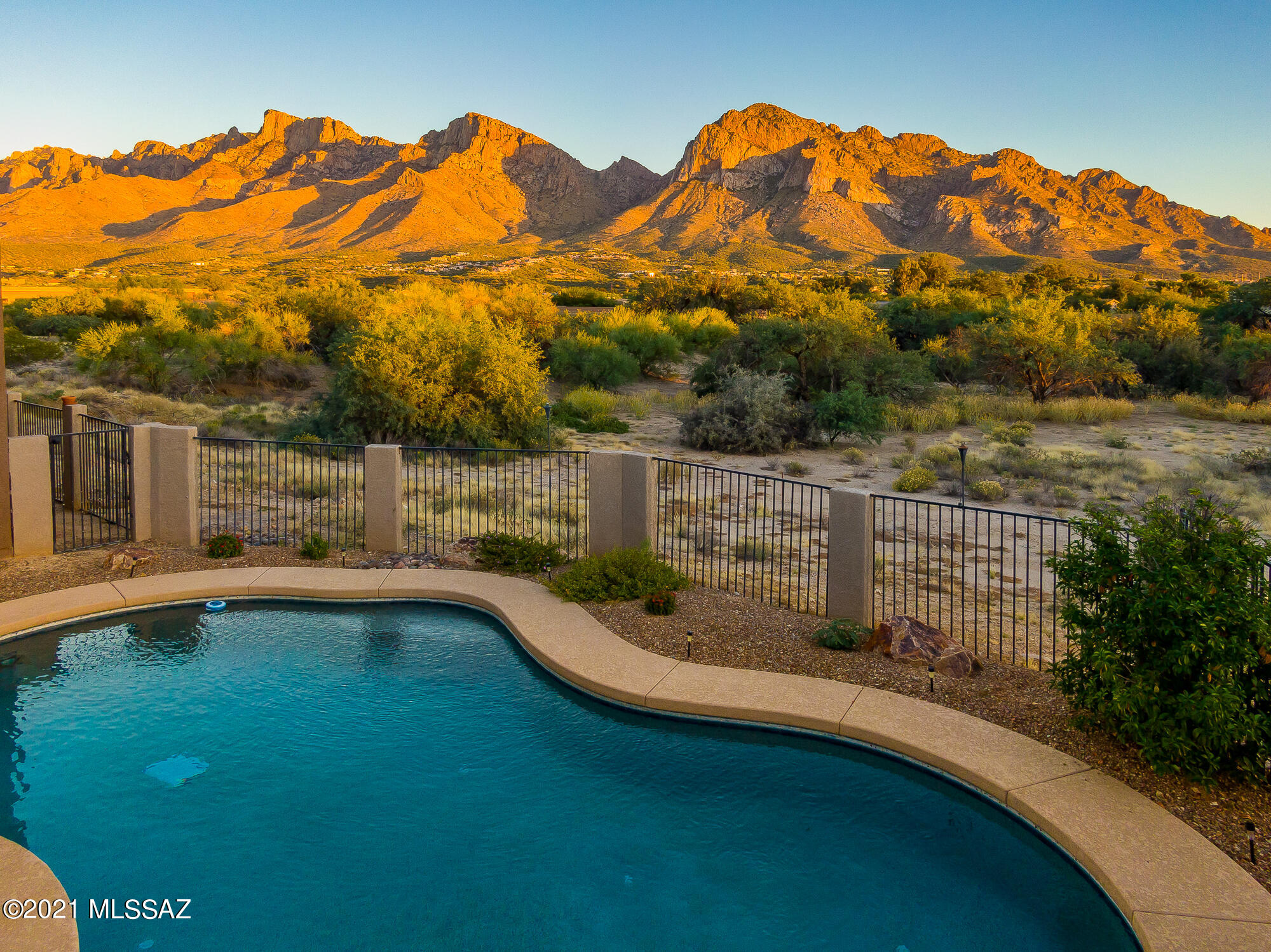 Oro Valley Retreat | No HOA | | Walled & Gated | .85 Acre | 4 Car | Fully-Owned Solar | Unobstructed Pusch Ridge Views | Contemporary design w/ stained & scored concrete floors throughout offers 3 living areas & formal dining. Entertainer's kitchen boasts, island, breakfast bar, eat-in area, stainless gourmet stainless appliances. Primary suite with extended walk-in closet, zero-entry wrap-around shower, cast-iron claw foot soaking tub. An oasis of a yard highlighted by sparkling pool, multiple seating areas, entertaining ramada w/ built-in KitchenAid multi-function grill, tile counters, stacked-stone surround, and prep sink. Brand new 40-panel solar system w/ 20-year dual warranty. RV ready. Bike & walking path connect to River Park & The Loop. *Video, Virtual Tour & Floor Plan in Photos*