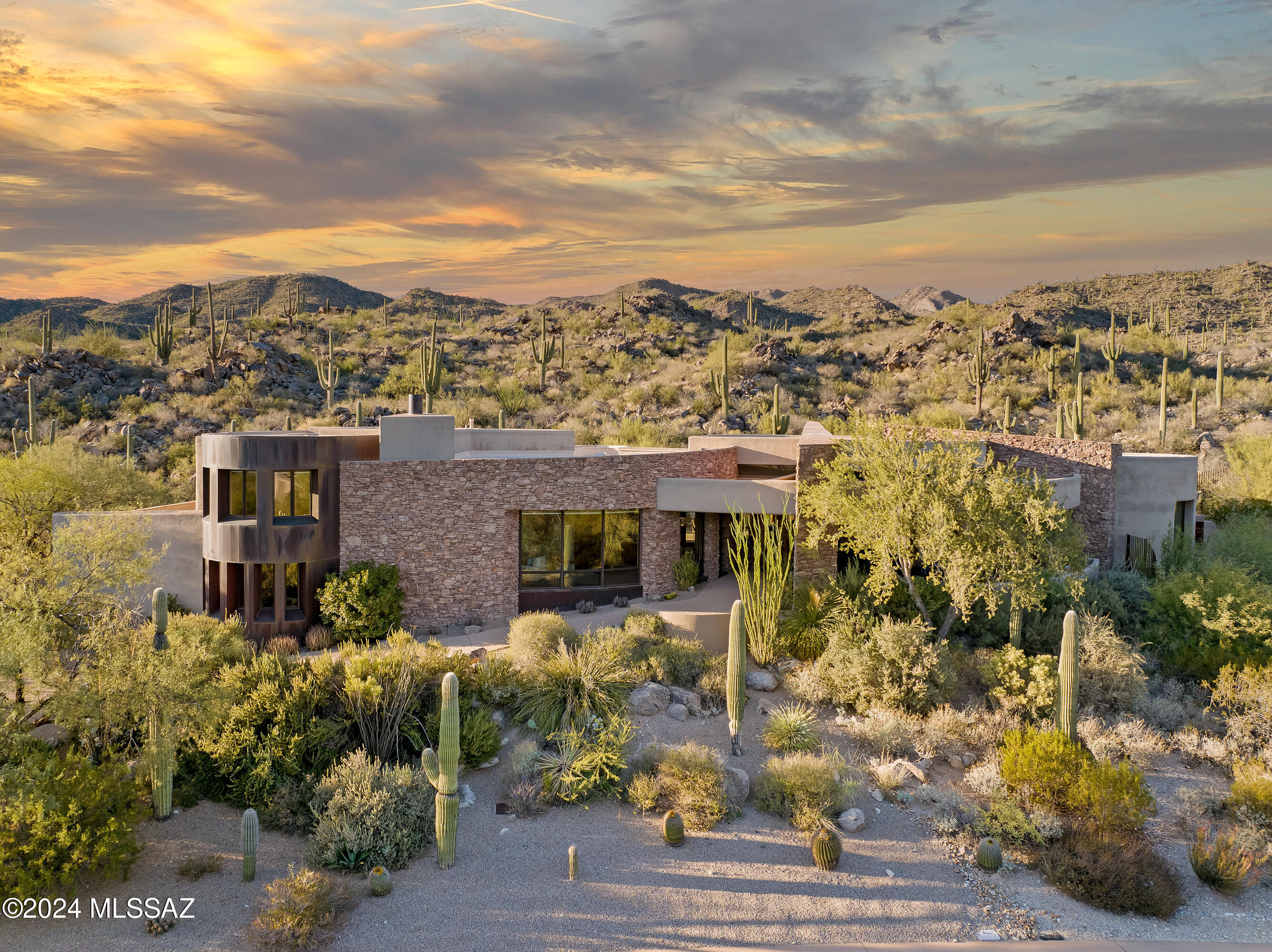 This timeless Ron Robinette design gracefully blends soft curves with rugged desert beauty on 3.69 acres in the highly sought-after Stone Canyon community. The setting is unmatched, with breathtaking views of the Catalina Mountain range, the lush golf course, vibrant sunrises, and sparkling city lights.
Upon entry, you're greeted by sweeping vistas of dramatic boulder outcroppings, a cascading waterfall, and thoughtfully designed living spaces. The kitchen opens to curved walls of glass, framing panoramic views of the mountains, desert, and golf course, while flowing seamlessly into the breakfast nook and great room. Natural, earthy materials such as sandstone tile flooring, hickory wood cabinetry, and granite countertops create a warm, organic ambiance. Three fireplaces—located in the great room, living room, and primary suiteprovide cozy comfort during cooler desert evenings.
The oversized garage offers abundant storage and an elevator leading to the main level and upper floor. Upstairs, you'll find two private en suite bedrooms, and an upper level laundry room offering unparalleled convenience. The main level encompasses all primary living spaces, including the impressive master suite, patios, kitchen, great room, laundry room, and a spacious office that inspires productivity with serene desert views.
With all baths updated and a few new touches in the kitchen, this home has been thoughfully curated in all of the right places.
Stone Canyon is consistently ranked among the nation's top golf courses and offers an array of amenities, including a championship golf course, a stunning swim and tennis center, and a well-equipped health club. Membership details available upon requestthis is a lifestyle like no other!