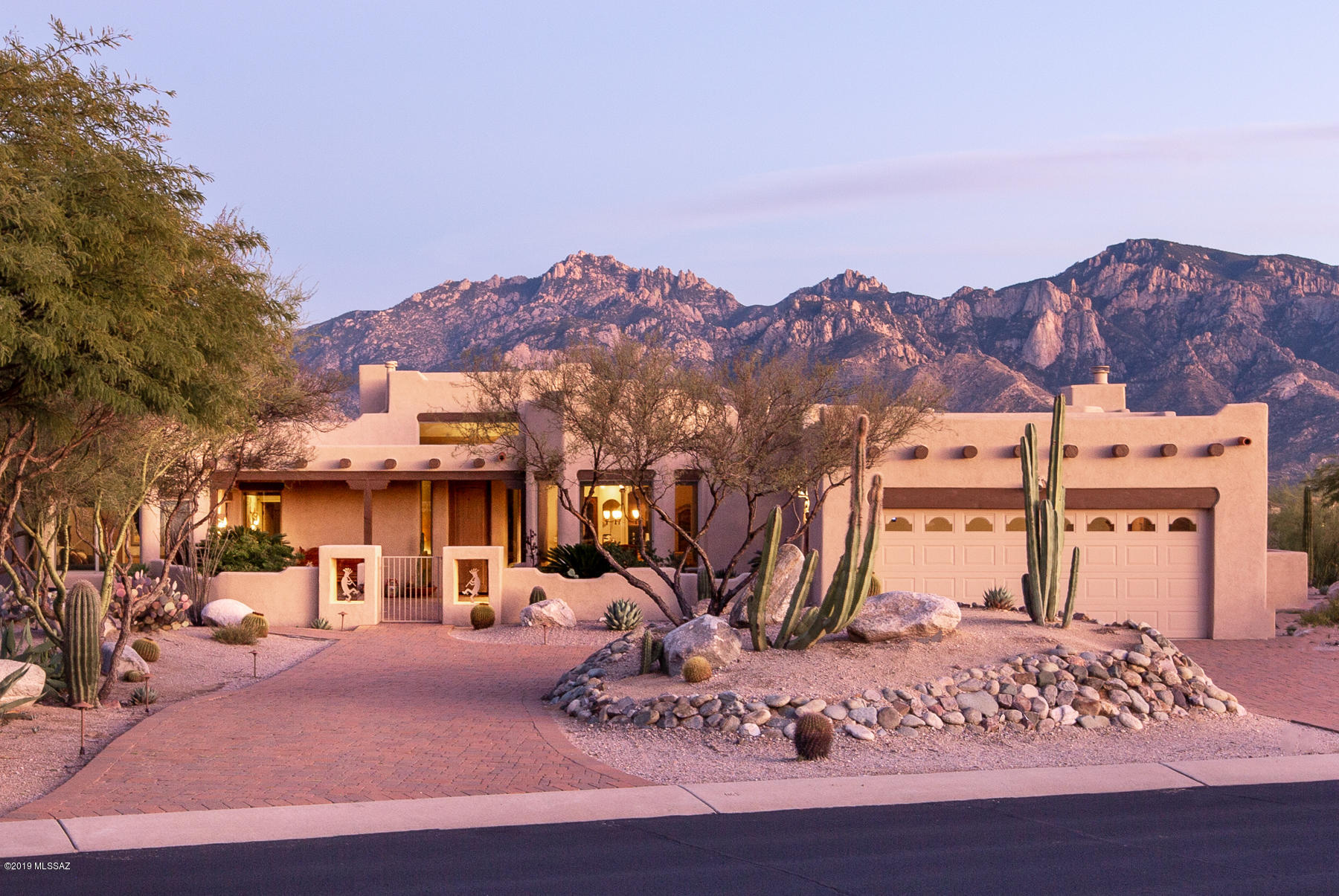 STUNNING SANTA FE STYLE HOME WITH SPECTACULAR SANTA CATALINA MOUNTAIN VIEWS! Built in 1998 by Mike Almli, this 3005 SqFt, 4 BD, 3 BA custom home sits on a 1.41 acre hillside lot with a vast natural desert wash behind that protects the breath-taking MILLION-DOLLAR MOUNTAIN VIEWS. Located in the highly sought after small gated custom home community of The Estates of High Mesa, this Santa Fe Style Home is a MUST SEE! From the moment you enter you will be captivated by the breath taking views, as oversized windows take full advantage of the Catalina Mountains throughout. This Santa Fe Beauty is perfectly suited for relaxing or entertaining guests, and stays true to its style with Saltillo tile flowing throughout the main house.Features include a large Living Room, sizable Formal Dining Room that seats 8, chefs Kitchen with tons of storage and work space, granite countertops, large island with prep sink, gas cooktop, breakfast area, desk with overhead storage, and hall pantry. The kitchen is open to the impressive Family Room, featuring Vega Beams, a beautiful built-in entertain center with gas fireplace, wet bar, and backyard access. The split bedroom floor plan offers a Spacious Master Bedroom, featuring a coffered ceiling, bay window, back patio access, large walk in closet, ensuite bath with travertine flooring and tile, separate vanity, walk in shower and jetted tub. BD 2 features front courtyard access, bay window, walk in closet, and ensuite bath. Located on the opposite side of the house is BD 3 featuring a built in desk, and BD 4 with a walk in closet. The Guest Bathroom is conveniently located to accommodate BD 3 & BD 4, and features a duel vanity and tub with shower. The East facing backyard is truly an oasis in the desert that is perfect for entertaining or relaxing, as it features a lagoon style pebble tec pool and spa with cool decking, an expansive partially covered paver patio that accommodates plenty of seating, charming gas beehive fireplace, beautiful mature plantings, and stunning panoramic Catalina Mountain Views. Additional features include a spacious Laundry with a utility sink and plenty of counter space and storage,  2 Car Garage with a built in storage room, large paver front courtyard, professionally landscaped yard with irrigated mature plantings, paver walkways leading to front and back of house, and circular paver driveway for ease of coming and going. However, once you arrive you are never going to want to leave, as this truly is ARIZONA LIVING AT ITS FINEST!