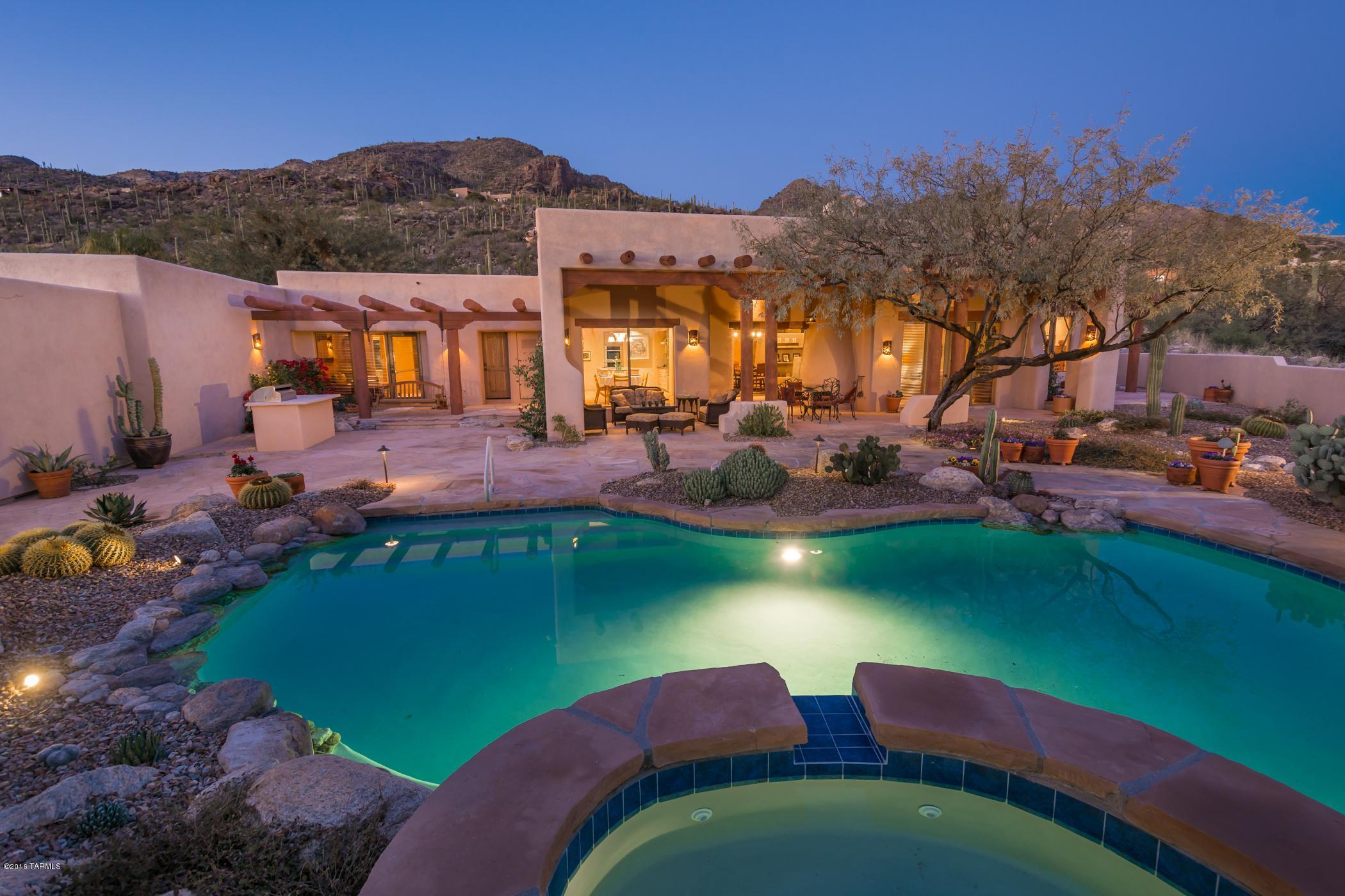 This classic Sante Fe home has all the modern conveniences and is situated on almost an acre of privacy. The property is on a corner lot in a desirable, secluded portion (with only 19 homes) in gated Ventana Canyon. There are over sized vigas, solid wood Butler doors and artist rendered hardware throughout. Hand painted Mexican tiles, 3 adobe beehive fireplaces and built-in niches for added charm. Custom iron gates. Split 4 bedroom plus den plan. Located among shady mesquites , the beautiful landscaped back yard with assorted flagstone patios, built-in BBQ and fireplace is perfect for relaxation or entertaining. Re-plastered pool. Level driveway, ample parking with quality pavers and 3 car garage with adjoining storage room.