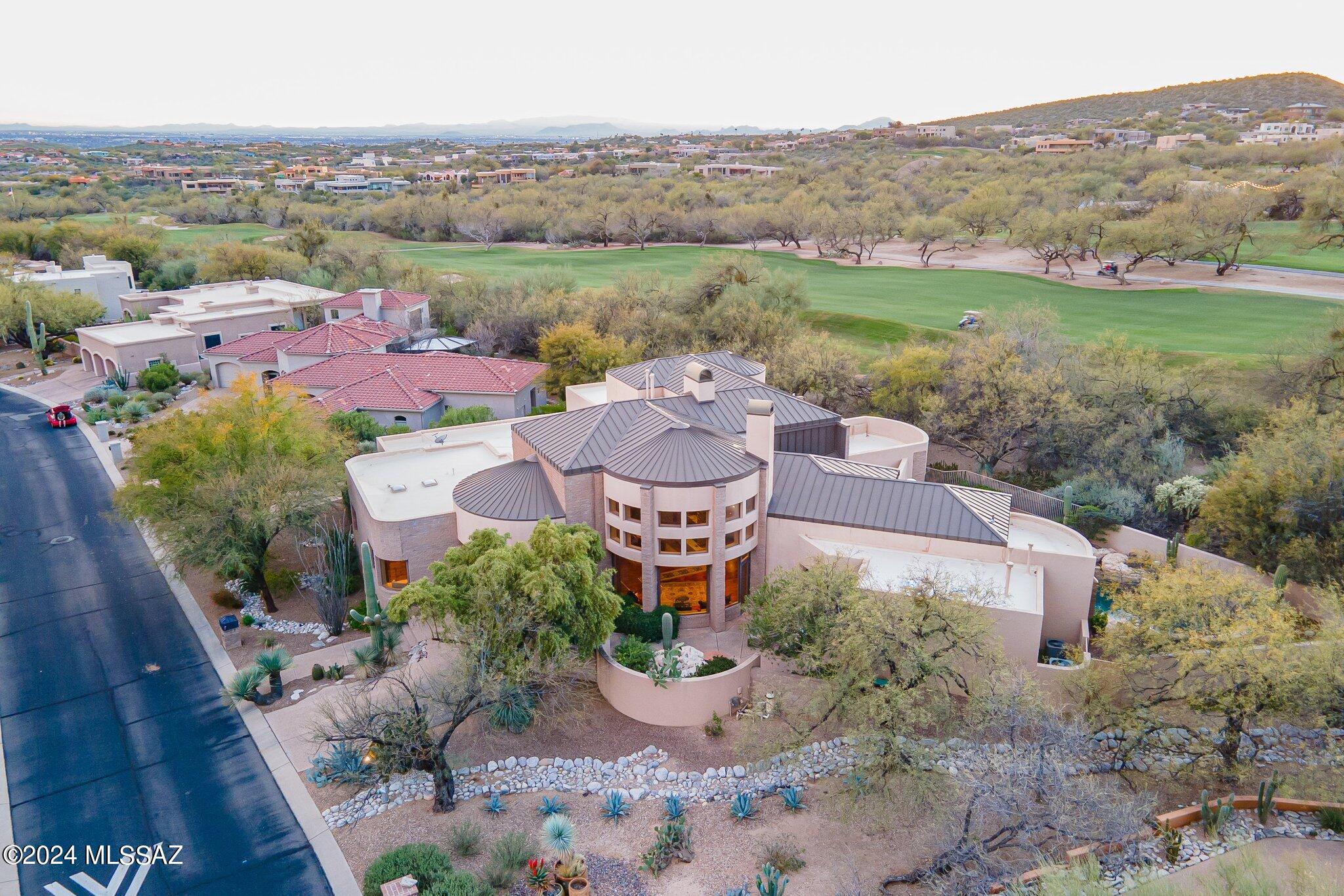 Warmth, Quality, & Charm Exude From This Exquisite Southwest Contemporary on The Golf Course in Coveted Ventana Canyon - 5,023 SQFT  4 BR/4 BA -  Fine Features Include: First Level Main Living Spaces Including All Bedrooms - Mesquite Hardwood Floors - Great Room w/24ft Ceilings, Stone Walls & Stacked Stone Fireplace, Floor to Ceiling Windows - Recently Remodeled Kitchen w/ Quartz Counters, Wolf & SubZero Appliances all Opening to Great Room - Primary Suite w/ Fireplace, Courtyard, & Recently Remodeled Spa Like Bathroom - Grand Staircase (Also Elevator)  to  Office/Library Loft  w/ Viewing Deck - Oversized 2 Car Garage & Golf Cart Garage - Private Covered Back Patio w/ Built in Grill, Pizza Oven, and Sparkling Pool & Spa w/ Golf Course & Mountain Views!  This is Resort Style Living!