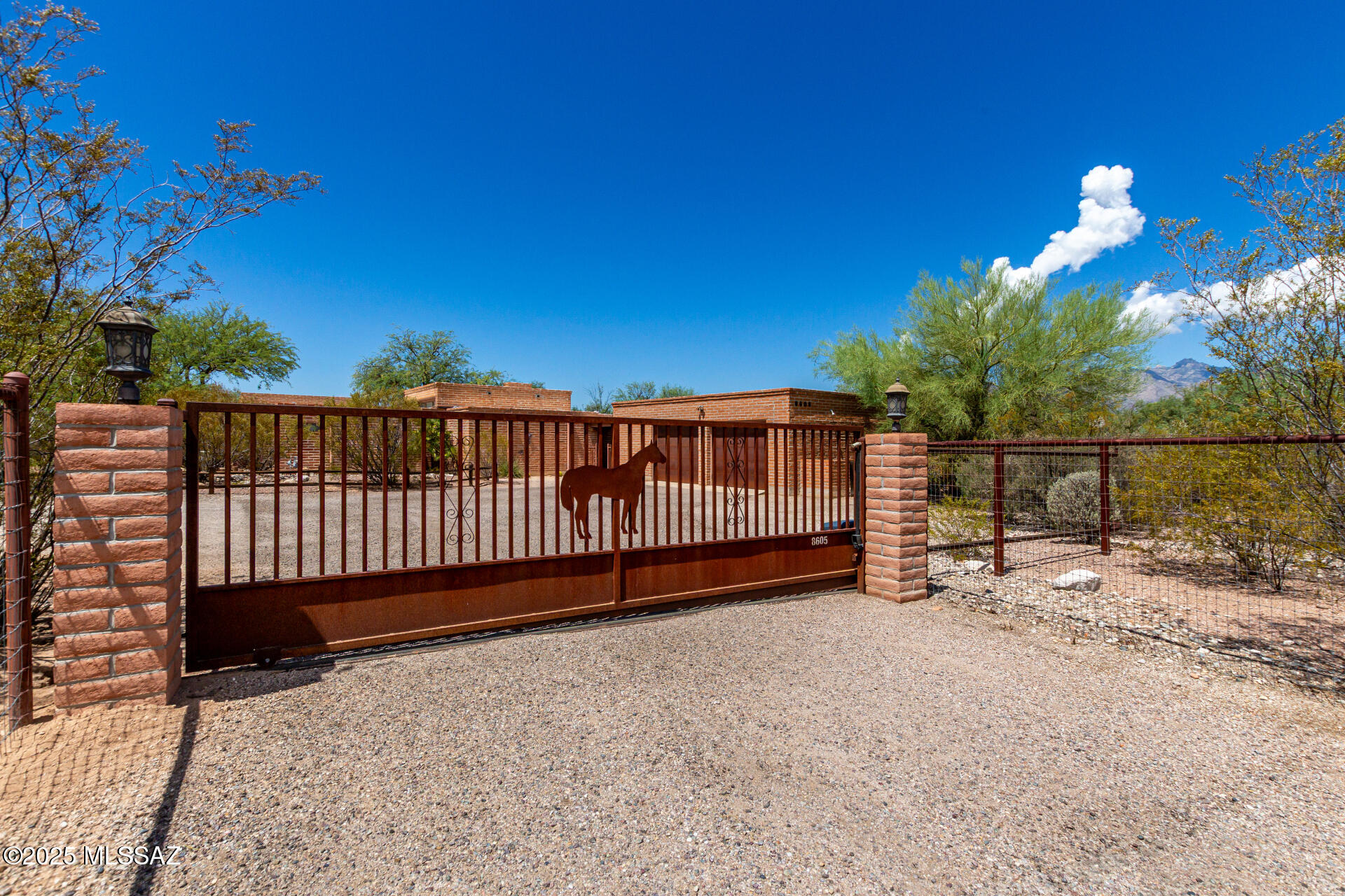 Elegant burnt-adobe home on over 3 1/2 acres is ready for your horses and other ranch hobbies. 4 bedrooms in the main house, plus a studio/guest house addition offers plenty of room for all. The formal living room/dining area doubles as a library and billiard room, and the enormous great room includes a bar and wine fridge. The granite kitchen island easily seats five, with extra room for cooking prep and storage. The primary bedroom has an attached office, ensuite bath and enormous walk-in closet. The central covered patio has views of the Santa Catalinas and is shaded by a mature mesquite tree. Other outdoor features include a diving pool, sport court, three-stall mare motel with hay storage plus a shade structure in the pasture, lighted turnout/arena, a screened garden and huge chicken run. Enjoy country living and close-by shopping and restaurants.