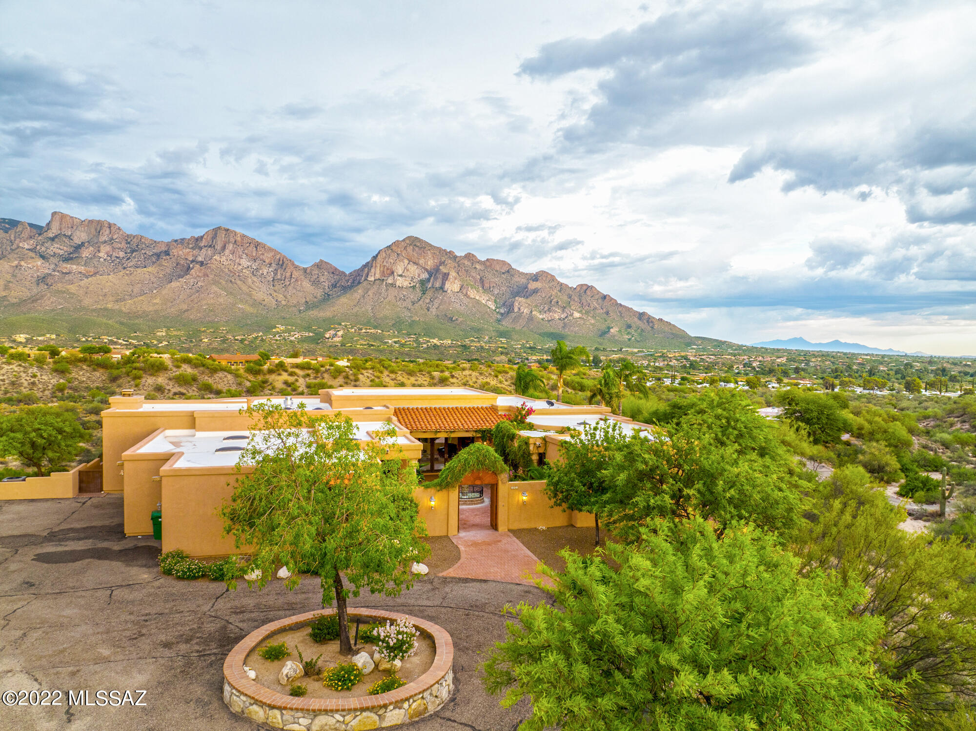 Nestled in the coveted Oro Valley Pusch Ridge community, is a gated enclave of private custom homes with unobstructed Catalina Mountain views. Enter through the Spanish Colonial courtyard surrounded with lush gardens, and carved Canterra stone infinity edge, flowing fountain, beautifully designed loggia-style entry flanked by arches and richly carved Cantera columns overlooks the sparkling pool/spa outward through views windows to Pusch Ridge mountain color drenched hues from sunrise to sunset from purple, pink, to yellow, each and every day. Move effortlessly throughout this single story 4200 square-foot home. It embraces 4 bedrooms, 4 bathrooms, chef's kitchen, and a formal dining room that opens to the sweeping terrace complete with unobstructed views in every direction through the pristine glass walls. Throughout the chef's kitchen you will find Stainless Steel Kitchen-Aid appliances. The rich cherry-stained Alder cabinetry is complemented by the luxurious chocolate-charcoal tones in the thick edge granite counters.  Enjoy the spacious curved island with a five-burner cooktop, complete with prep sink and disposal. Additional features include pullout drawers in cabinets, soft-closing drawers and a walk-in pantry. Adjacent to the kitchen is the family room where you can enjoy the commanding fireplace framed with Cantera columns, stone mantle and surround that extends to the ceiling. A wet bar and French doors welcome you to extend your living space outdoors to one of the backyard patios. The owner's suite is a luxurious retreat with custom cornices, a generous walk-in shower, walk-in closet with customized sectioning. Private views from the bedroom overlook the infinity pool with waterfall where the views extend out to Pusch Ridge, the Catalina Mountain Range and city lights! Car collectors will appreciate the extended and oversized garage with access to additional storage rooms and a tool workshop. The Extras: The property also includes large secondary bedrooms, a pool bathroom with house entry, and a 
Surrounded by land, a joyful spot watches the monsoons roll in over the mountaintops or stargazing.  This is a home for discriminating buyers that want ultimate privacy. This unique home has something for every family member and guests. View video.