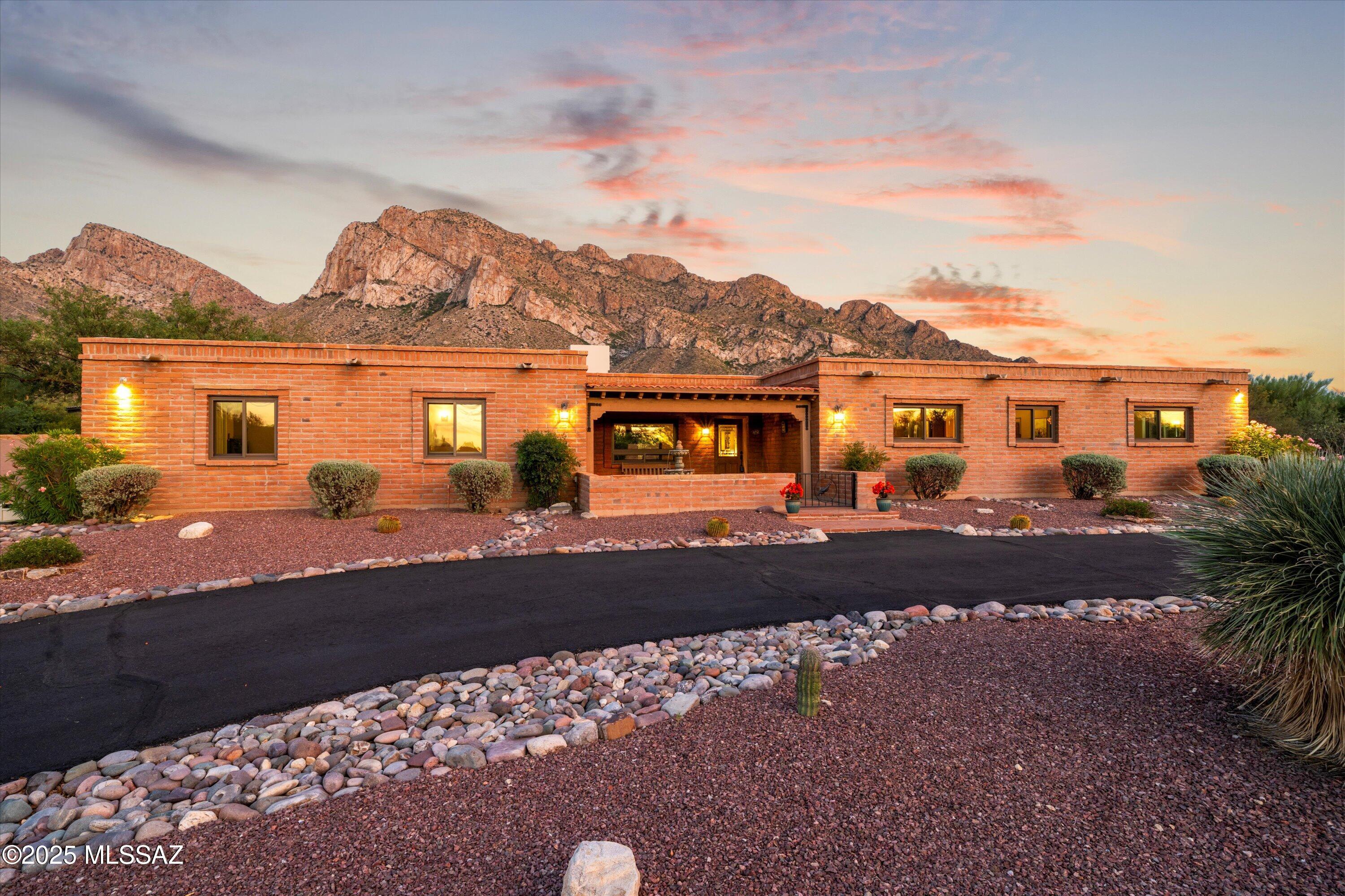 Pristine burnt adobe home situated perfectly to capture the stunning views of the Catalina Mountains in the heart of Oro Valley. Enter the property through the charming front courtyard with red brick pavers & a fountain. Once inside you will find an inviting floorplan that offers a split bedroom plan, family room with fireplace & formal dining area. Updated kitchen features beautiful granite counters, plenty of cabinets, tile backsplash, stainless steel appliances & breakfast bar. Primary suite is spacious w/slider to patio, walk-in closet w/built-ins, dual vanity & separate shower & garden tub. Newer Renewal By Anderson windows & doors '21, wood beams in numerous rooms, resurfaced driveway '25 & Saltillo tile floors are a few of the features of the home. Backyard is an oasis with...... .... jaw-dropping views of the Catalina Mountains, mature landscaping, extended covered patio, large turf area & pristine & replastered pool ('14), elevated sitting area & atrium off primary suite.