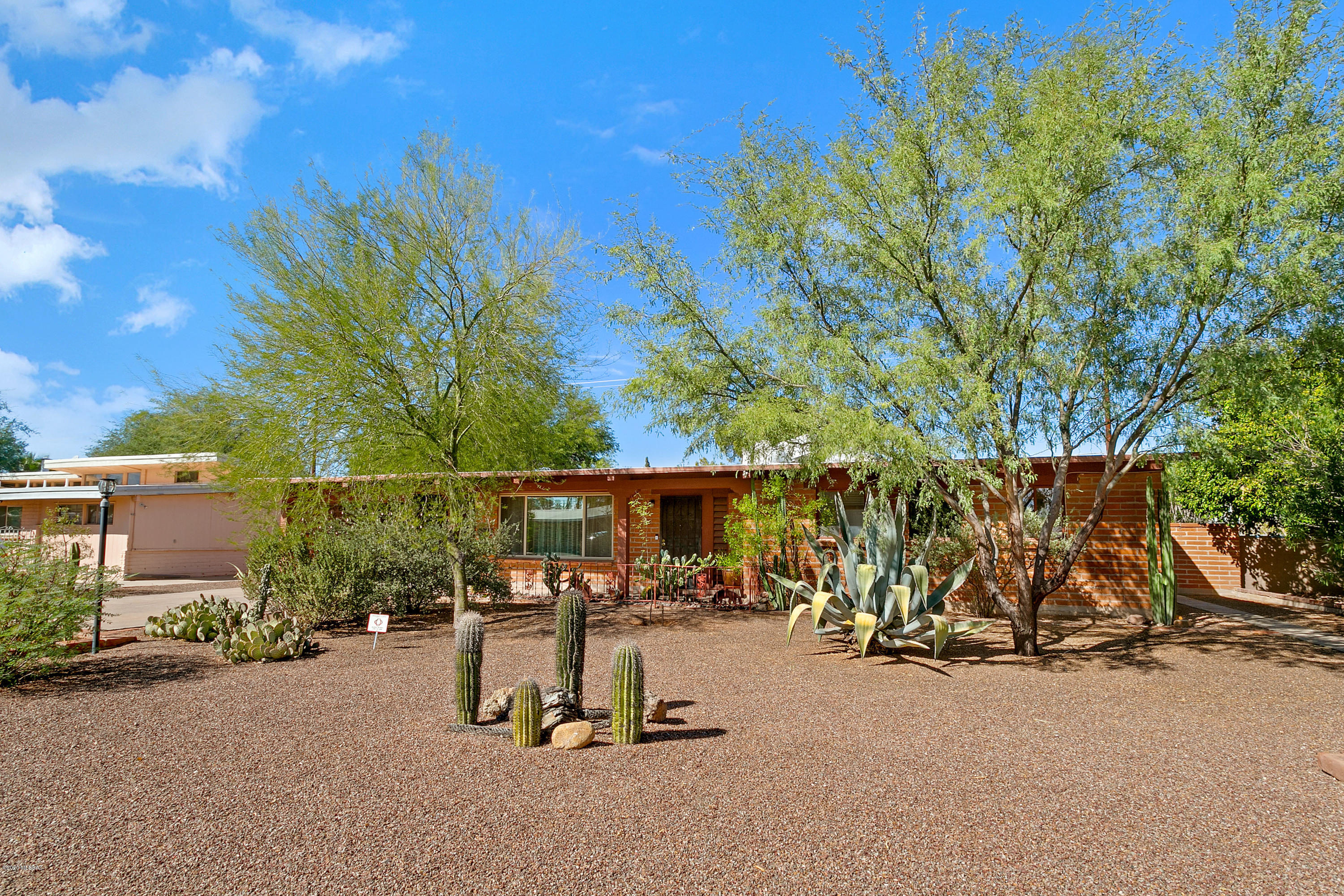 Privately situated burnt adobe Mid-Century home, full of charm. Vaulted tongue and groove beamed ceiling throughout the entire home. Large windows allowing lots of natural light. Large format neutral ceramic tile throughout living areas and wood laminate in bedrooms - no carpet. Recently updated kitchen with SS appliances, newer countertops with tile backsplash. Spacious bedrooms w/en suite owner's bath with new tiled shower and fixtures. Separate laundry room with washer and dryer and charming screened in porch at back. Many native plants and gardens in pool size back yard. This is truly an in town oasis, not to be missed!
