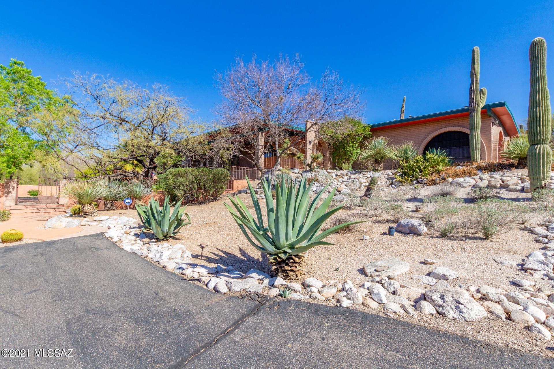 Gorgeous Energy Efficient Solar Hillside Home w/breathtaking Mountain views.  Impressive desert landscape! Soaring ceilings w/wood beams, beautiful tile floors throughout, custom palette, ceiling fans, fireplace for the chilly AZ evenings, built-in bookcases, & formal dining area w/veranda access. Open floor plan, handsome wood interior doors, & Bonus guest house! Center kitchen island, granite counters, breakfast bar, SS appliances, pantry, & plethora of wood cabinets w/hardware. Living room opens to the pool and patio. Private den, generous size bedrooms, ample closets, interior laundry room, & upscale pristine baths. Sparkling pebble tec pool, built-in deck benches, covered patio and bathhouse. Expansive porch with spectacular views of the Catalina mountains. Gorgeous mature landscaping