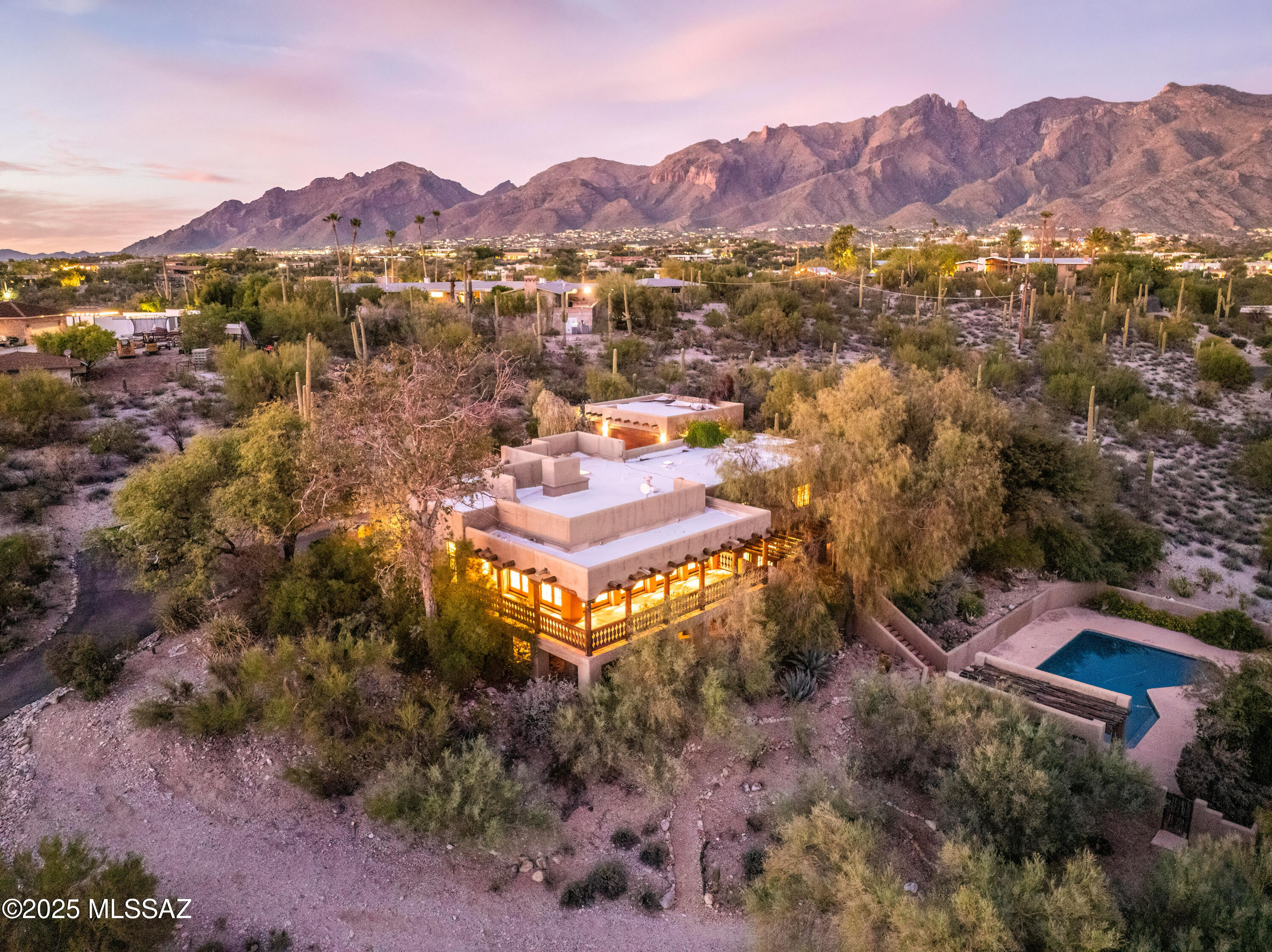 This stunning Santa Fe-style Foothills residence blends a perfect sense of timeless charm with  modern comfort. It features four bedrooms and four baths, highlighted by Viga beam ceilings, warm wood and Saltillo tile floors, and four cozy wood-burning fireplaces. The chef's kitchen offers granite countertops, a large butcher block island, and abundant cabinetry. Enjoy multiple living spaces including a generous family room with a built-in bar that's perfect for entertaining or large gatherings. Stepping onto the wraparound balcony, you'll be greeted with breathtaking city lights and Catalina Mountain views while you relax by the sparkling blue pool and serene desert landscaping. A true Southwest retreat combining elegance, character, and unforgettable views.