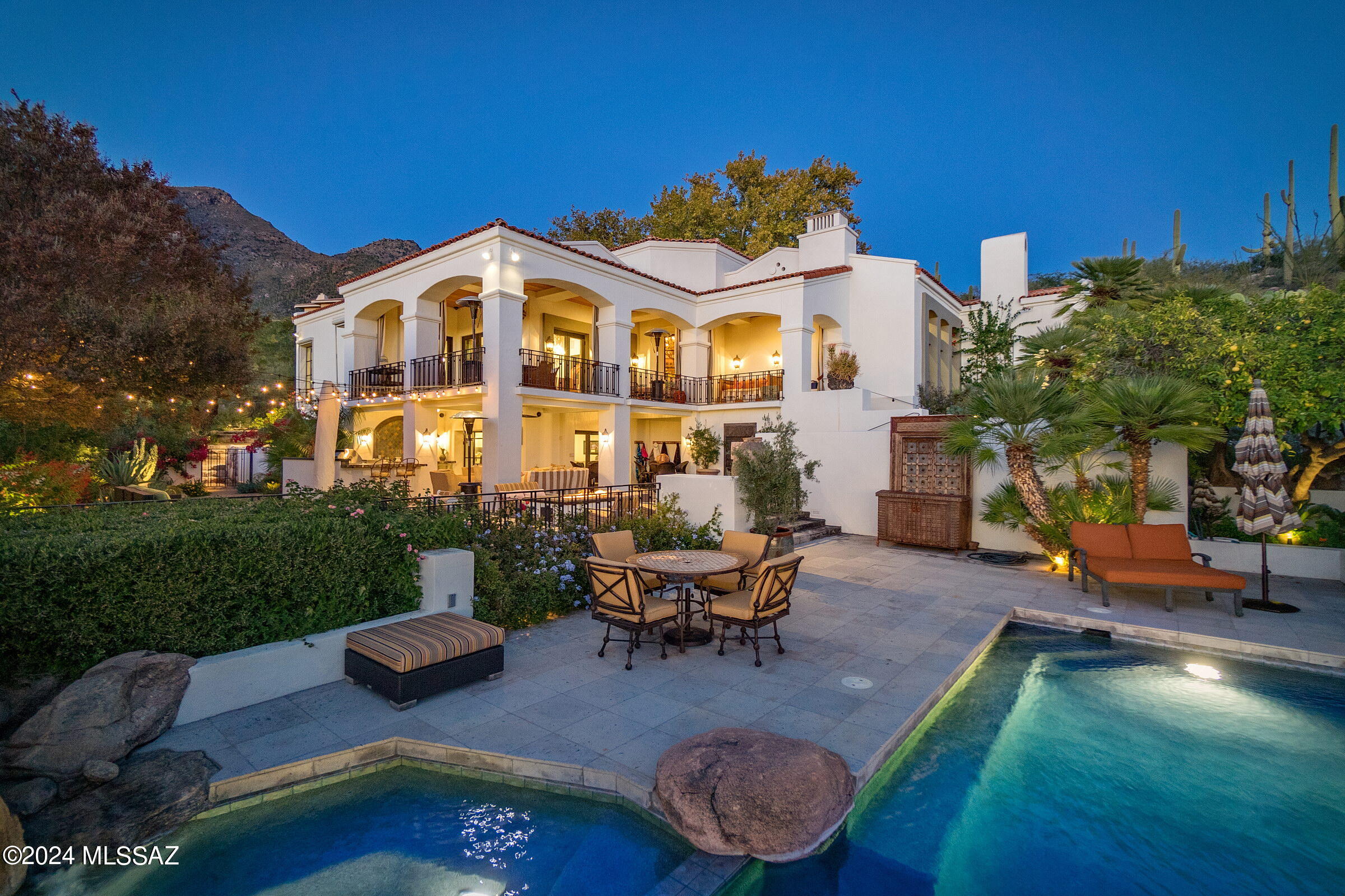 Situated on a commanding view lot overlooking the greens of the 1st fairway, this adaptive estate home demands privacy while preserving views that open out to the far reaching vistas of the adjacent Catalina Mountains, with the expansive city lights beyond. As one travels between the individual spaces, dramatic landscapes unfold, allowing for an abundance of natural light from every room. Transparent facades and French doors fuse indoor and outdoor living environments, used to derive a sense of spatial richness. This estate integrates cutting-edge technology through the use of an interface automation for sound and security. The fit out and quality of finish is incomparable, proportioned with elegant architectural features and large steel casement windows that provide expansive views overlooking the established grounds. The home's interiors feature the highest quality materials, adorned with reclaimed solid oak wood floors, juxtaposed against an inlay of Spanish deco tile, with a cohesive blend of custom cabinetry styles and finishes featured throughout the residence. Whitney recessed oak is brilliantly contrasted against black espresso millwork, with open pore wood treatments, fitted in a combination of quartz and granite surfaces. From the warmth of timber to the cool touch of stone, materials were carefully selected and meticulously detailed to evoke a sensory experience that resonates with the human spirit.

The design facilitates 4 bedrooms and 5 bathrooms with a main level owner's suite, luxurious bath, stone clad walk-in shower and private garden retreat. One additional en-suite bedroom is housed on the main level, with all supplementary en-suite bedrooms discreetly sequestered on the lower level, physically connecting the interior to a generously shaded veranda, creating a gradual transition from the materially warm interior spaces to outdoor living and entertainment.

A negative edge pool emerges as a floating cube with its surface mirroring the graceful branches of the surrounding Palo Verde and Desert Mesquite trees. Existing foliage forms a visual frame around the home's landscape that plays against artful compositions that punctuate the outdoor spaces. Areas to lounge and gather are thoughtfully positioned throughout the exterior, serving as the framework to experience distinct outdoor living spaces, each offering its own unique flavor.