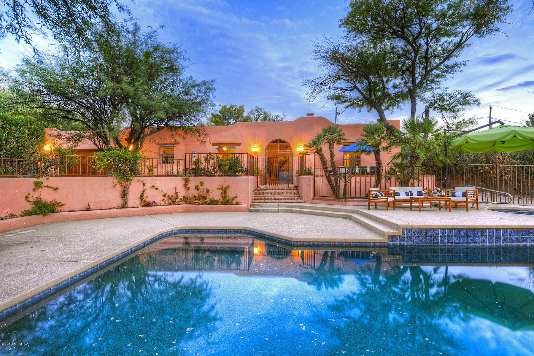 Stunning mud adobe stucco home in the Ft. Lowell Historic District on an oversized .51 acre lot with 3 bedroom, 2,691 sq. ft. main house and 555 sq. ft. detached guest house.  Located in picturesque Bosque Ranch (within a mesquite forest) near Ft. Lowell Park, enter compound through gated exposed mud adobe wall, over red brick walkway to trellised courtyard entry.  Enter great room featuring ceilings with hand-carved beams, corbels and saguaro ribs, rustic wooden lintels above windows and doorways, exposed adobe walls, beehive fireplace, Saltillo tile floors and adjacent den/media room.  Expansive kitchen has oversized butcher block island, master suite offers beamed and saguaro ribbed ceiling, beehive fireplace, dual walk-in closets, master bath with dual Talavera tile sinks and adjacent, private atrium/patio.  Charming guest house has arched entry door, brick floors, beamed and planked ceiling, beehive fireplace, full kitchen and bath.  Plenty of yard space including pool, spa, mesquite trees and so much more.