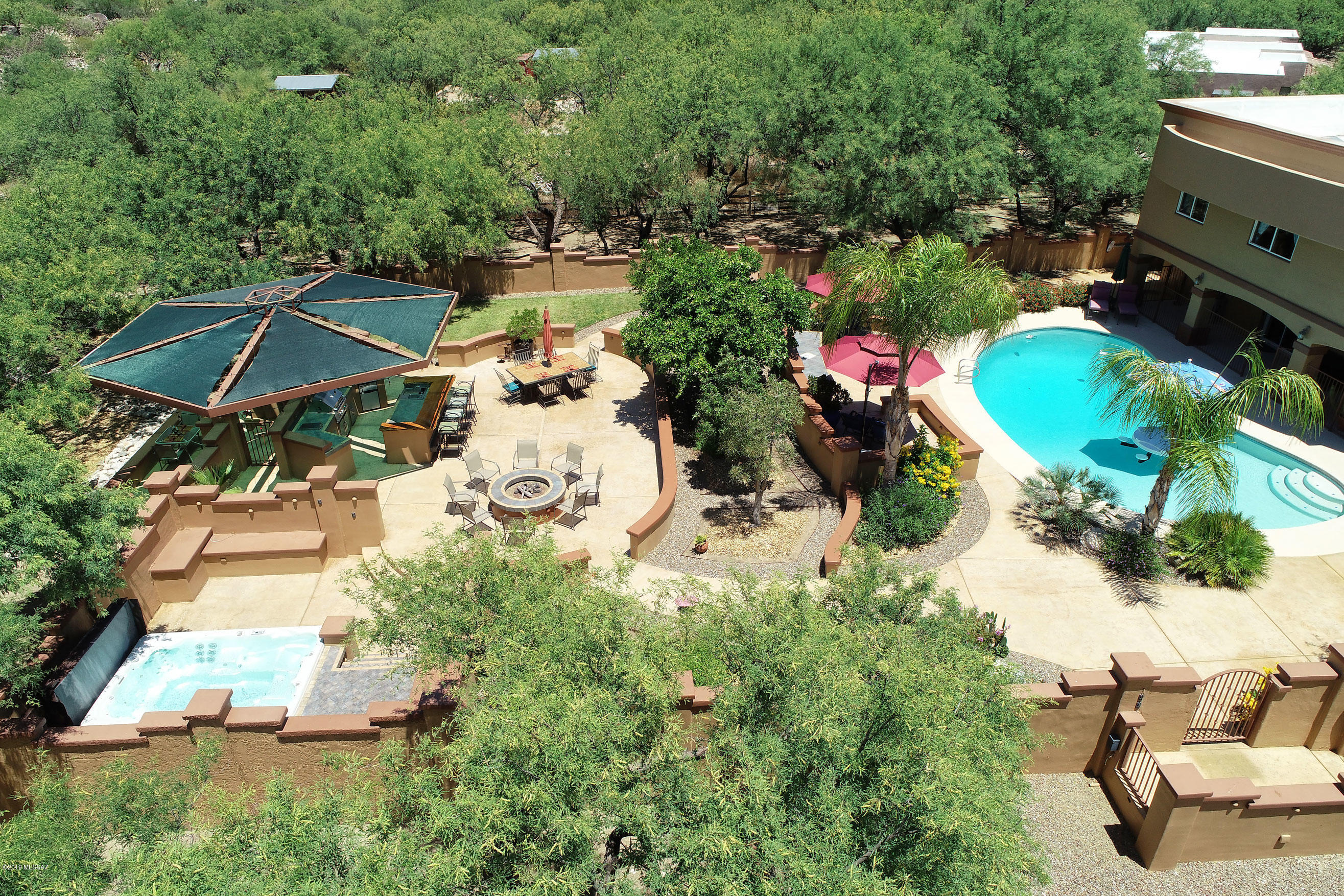 ''Incredible astounding estate'' barely begins to describe this gated nature preserve with a lovely home. Who wouldn't want a fabulous luxury resort in your own backyard? The 3.2 gorgeous acres of manicured mesquite bosques and saguaros, mountain views with an elegant yet cozy home is perfect for families, multi-generational living and over-the-top entertaining.  At an excellent price on Tucson's verdant and vibrant Northeast side, you have a recipe for gracious living. The entire property, named Mesquite Rose Ranch by its owners who have made huge improvements, is spectacular. This is one of the best properties we have ever seen in Tucson at this price, and we see a lot of homes! The huge back yard resort encompasses not only a large elegantly curved pool surrounded by roses and palms, but shaded patios, lush irrigated gardens, a huge entertaining pavilion with creatively shaded outdoor kitchen featuring newer large barbecue with side burners and two refrigerators + sink, large dining area (Can you imagine the fragrance of old-fashioned barbeque dinners wafting over you?), TWO firepits and an oversized covered spa for the family plus friends. And did we mention the night-lit tennis court for playing in the cooler evenings and the putting green? If that's not enough, walk through one of the rose-accented gates and down to the stream below the entertaining/recreational areas (River-front property in Arizona?).  And what a great spot to see the abundant wildlife...hummingbirds galore, deer, coyotes, a resident bobcat, quail and javelina families. A tack barn is currently used for storage but could be converted into a workshop. The just-repaved elegant circular drive leads to a river-rock enclosed courtyard and full front porch welcoming guests into the one-of-a-kind home filled with history, character and charm. The very livable home, elegantly updated in soft desert tones, encompasses 4 large bedrooms, 5 baths, rich solid mesquite cabinetry throughout, and multiple spaces to gather, chat, work out, entertain and relax. From the rich entryway and through the lovely parlor with river rock fireplace, the home continues to a bar area with mesquite counter and bench, copper sink and double wide glass front refrigerator, and a lovely kitchen with handsomely shaded granite counters, Jenn-Air 6 burner gas stove, and rich mesquite cabinets overlooking the pool and gardens. A charming powder room is nearby. The family room is spacious and comfortable, great put-your-feet-up space, with an adjacent powder room. A formal dining room with a coffered ceiling providing soft lighting creates an enjoyable ambience for special dinners. Head upstairs via one of the two mesquite-step stairways for a fabulous cornucopia of living spaces. An upstairs sitting room with fireplace enjoys its own bath with a large glassed-in steam room with two levels of granite seating. There is also a dining alcove enjoying views over grounds of mesquites and to the mountains and its own terrace. A recreation/work-out room with full mirrored wall (getting these mirrors installed was an adventure!) and disco ball with bamboo flooring for dancing, should one be so inclined, is the spot for the work-out equipment. The giant master bedroom suite with sweeping mountain views and cozy sitting area by the contemporary fireplace, is fabulous....and step outside to one of the two terraces for a breath of fresh air and one more delightful spot to enjoy a cup of coffee in the morning. The master bath area is stunning, with glass door out to the private terrace, a huge Jacuzzi tub set into a gorgeous granite surround, matching granite counters including a seated make-up spot for the Princess of the home, double sinks, walk-in shower with views, and two ample walk-in closets. Even the WC has views, along with a Toto washlet commode. Three additional charming spacious bedrooms enjoy views and share a hallway raised sitting area and cozy hallway bench and a large full bath. The laundry is nearby, how sensible-No carrying laundry up the stairs! Art niches and shelves for books and art abound, as does storage space. Flooring throughout the home is a handsome combination of 12" rich slate tiles, richly polished mesquite, and carpeting in guest bedrooms. There's no HOA but the neighbors keep everything looking great and there is much pride of ownership. The neighborswatch out for each other and are friendly. It's horse territory and they often see neighbors out for a stroll on their horses. The subdivision name of La Bella Vista certainly seems appropriate! Additional history: When the owners purchased this property, the back yard was an empty pool and nothing else. They got married in the rather bare backyard and then set to work to create the oasis that you will see now. Beautiful furniture may be available per a separate bill of sale. Truly a labor of love! Call us today for your private showing.
Current appraisal of $925,000 by Ira Gold appraiser is available upon request.