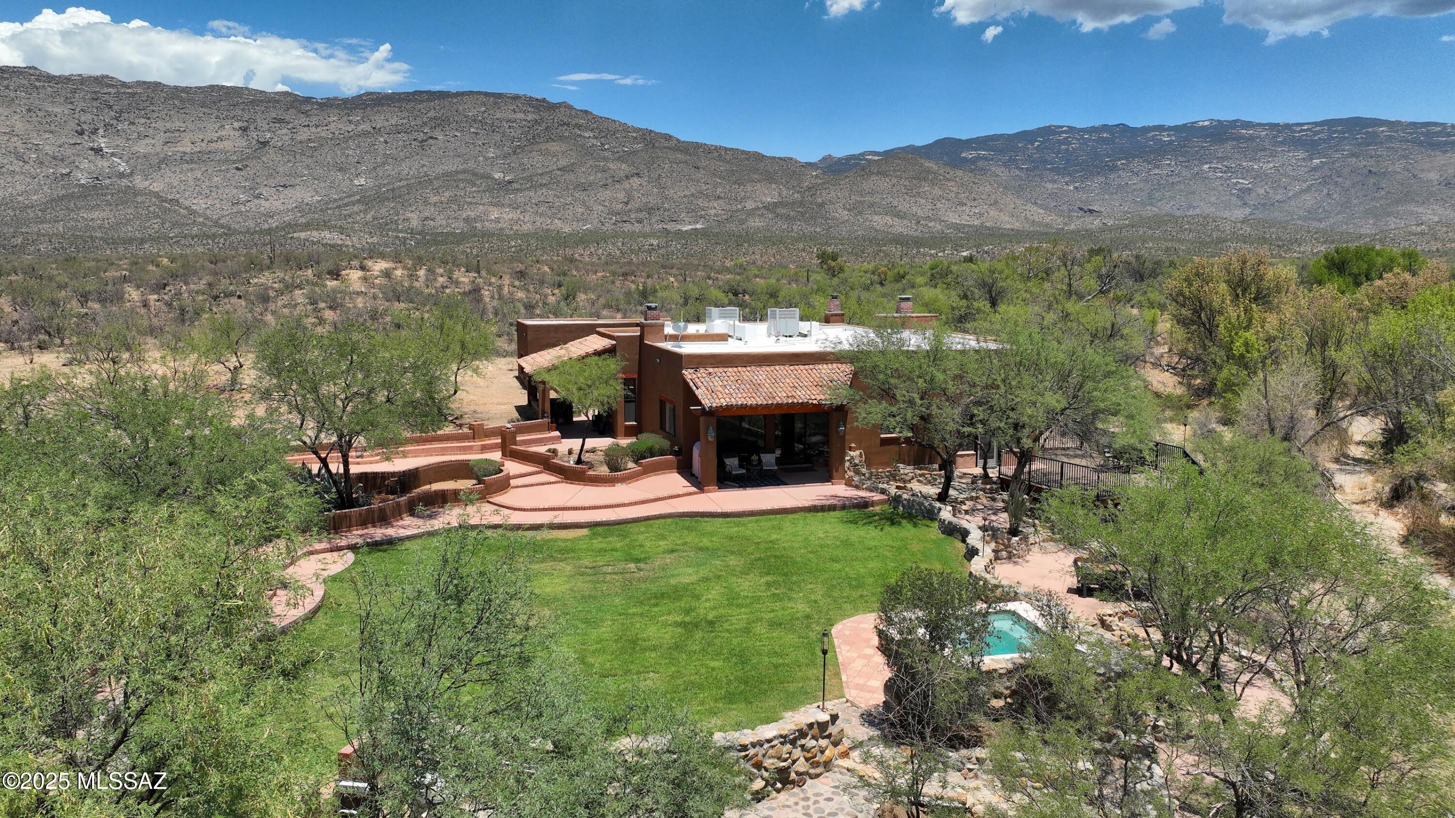 One-of-a-kind property offering breathtaking Rincon Mountain views on over 6 acres of natural desert beauty & direct access to state land with a seasonal creek running through. Ideal for outdoor lovers or anyone seeking privacy & space. 3,620 SF main house features wood ceilings, flagstone accents, Saltillo tile floors & lg picture windows that frame the stunning landscape. Lovely kitchen w/granite counters & abundant storage. Generous primary w/FP & more views!  1BR/1BA, 600 SF Gst Hse w/panoramic mtn views sits above a flexible wkshp/studio/garage + sep 2 car gar currently being used as a fully functioning blacksmith shop. Take in the scenery from the raised deck or unwind in the spool after a day on the nearby Arizona Trail. Comfort, character & the freedom of wide open spaces awaits.