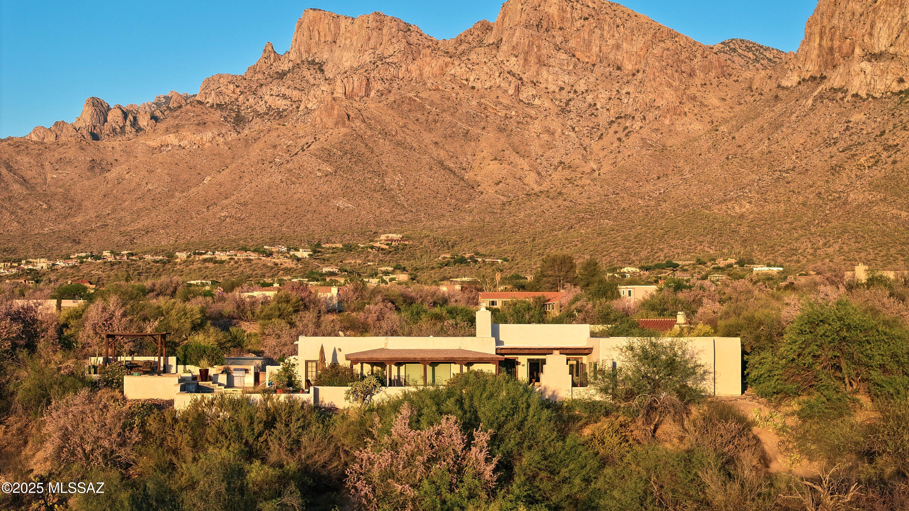Nestled on a hillside 1.3-acre lot and within the prestigious Oro Valley Country Club, this stunning 3,025 sf 3-bedroom, 3.5-bath custom residence perfectly blends sophistication and comfort. A cobblestone driveway welcomes you to a private front courtyard featuring a wrought-iron gate, rustic sconces & peaceful garden setting w/Catalina Mountain views. Inside, the Formal Living Room exudes Southwestern charm w/ exposed wood-beam ceilings, natural travertine flooring, & a wall of windows that fill the space with light. Steps away, the spacious Great Room features a custom-built media center w/rich wood cabinetry, fireplace, dining area, and artful alcoves. The gourmet kitchen is a masterclass in elegance & function, Highlights incl. custom cabinetry with professional Wolf appliances, cont Pot-filler faucet, hand-carved wood hood, dual ovens including steam convection, Sub-Zero refrigerator/freezer, wine fridge, and a striking wrought-iron chandelier over the spacious island and breakfast bar. Built-in pantry and artisan finishes complete this impressive space, the heart of the home. The Formal Dining Room has a matching granite shelf and overlooks the front courtyard and the Catalina Mountains.

Outdoor living shines with a multi-level patio offering panoramic mountain views and resort-style amenities. Enjoy the elevated pool and spa, complete with a relaxing water feature, lush landscaping, and a spacious stone terrace that leads to a ramada-covered lounge with a fire pit, a built-in BBQ, and a Green Egg smoker. An additional courtyard with a tiered stucco fireplace provides a cozy spot to unwind under the stars.

The tranquil primary suite features high ceilings, neutral tones, and travertine floors, flowing into dual en-suite baths with custom tilework, walk-in showers, and rich cabinetry, creating a true spa-like retreat.

Additional features include two guest bedrooms, a beautifully designed laundry room with distressed cabinetry, granite countertops, a mosaic tile backsplash, and ample storage, as well as a two-car garage with built-in storage.

Enjoy country club living, whether it's a round of golf, pickleball, a relaxing walk around the community, a bike ride on the popular 131-mile multi-use "Loop," or the convenience of dining and shopping. Make this home yours today!
