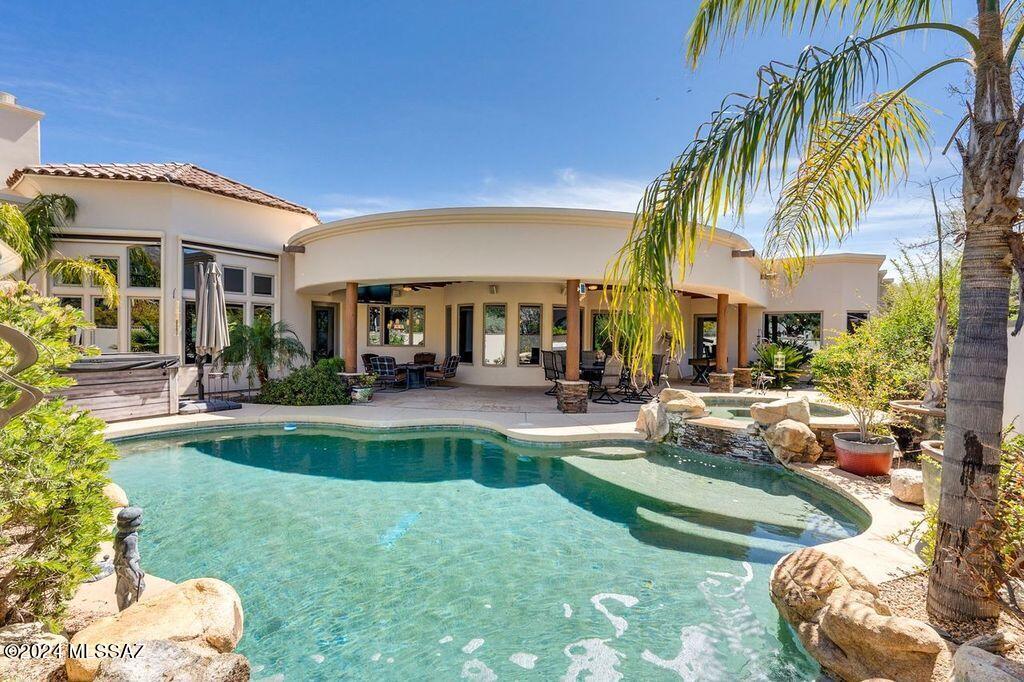 From the port cochre entry to the captivating waterfall, this home will impress even the most discerning. Nestled within the gates of coveted Ventana Canyon Estates, this contemporary home presents a Mediterranean flair featuring soaring coffered and pan ceilings w  crown  molding, travertine floors, 8' doors and thoughtfully placed columns. Stunning living area, formal dining, full service wet bar, family room w fireplace. Chef's kitchen has massive leathered marble central work island, cherry and maple cabinets, high end Wolf and Sub Zero appliances, large breakfast nook.  Generous primary suite with fireplace, beamed ceilings, jetted tub, spa-like shower with multiple controls & incredible walk in closet. Three more ensuite bedrooms, split plan for utmost privacy and separate guest quarters (mother in law suite). Guest quarters has ample living area, kitchenette, bedroom and full bath. Separate office near primary suite boasts walls of built-in shelving, high windows, wood flooring and double glass doors. 
Backyard oasis features pebble tech pool and spa with soothing waterfall. Flagstone hardscape, wrap-around covered patio and stunning mountain views. The flow from inside the home onto  the massive outdoor space is perfect for entertaining and family enjoyment.
More than ample storage space is provided with several walk in closets, built-in hallway storage and huge pantry.
Tandem 3-car garage also has work bench and 2 separate storage rooms.
No steps in home.
Only a minute by golf cart to the driving range!
Golf, tennis or social membership available separately allowing access to the numerous exceptional amenities of Ventana Canyon Golf and Racquet Club.