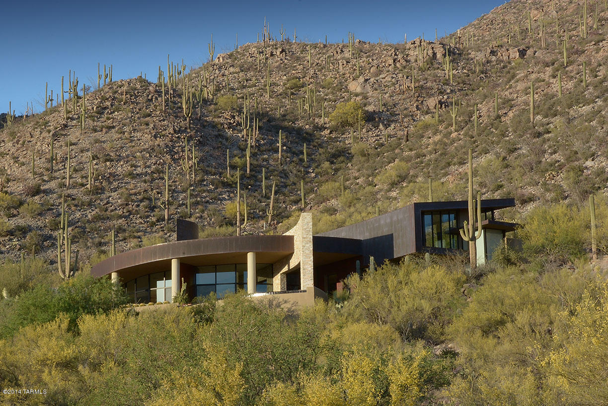 Range Price- Will accept offers between $1,699,999 and $1,799,999. As featured in Luxe and Tucson Lifestyle Magazines, this design-award winning home hugs dramatic rock formations, set on a spectacular hilltop lot with breathtaking panoramic vista views;  exterior is clad in ledgestone and patina copper, blending organically with nature's gorgeous surroundings.  Interior design by Lori Carroll is perfection, Windows everywhere strike the perfect balance between tall interior spaces and lifestyle intimacy; fabulous floorplan makes for casual livability, with a bonus den/office for a multitude of uses.  Everything the eye can see is stunning and practical at the same time.  Browse the photos to see for yourself and don't miss the gasp-worthy negative edge pool and jaw-dropping views