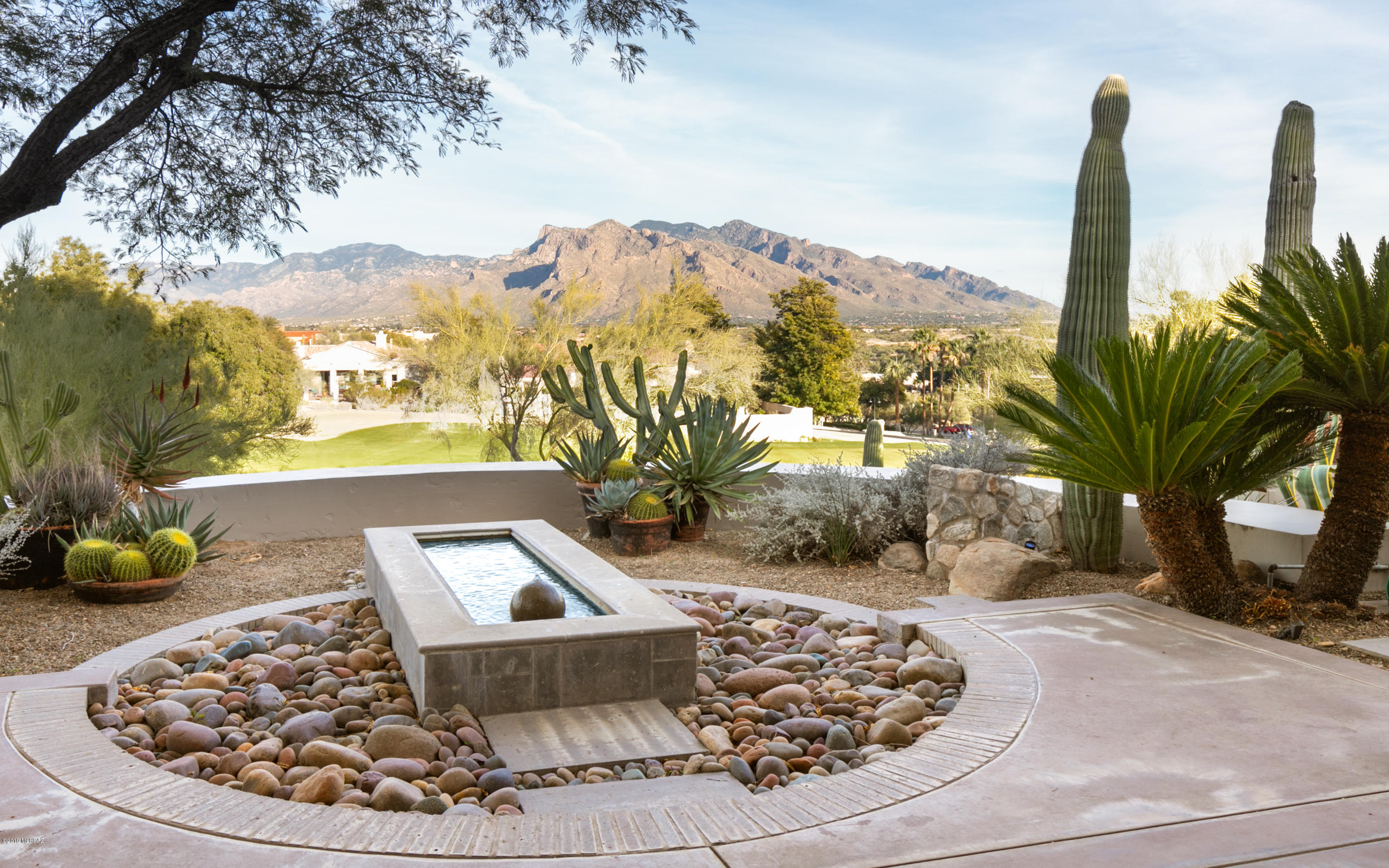 Gracious & spacious, custom built Old Pueblo style home on 2.03 acres. Located at the Gated Omni Tucson Golf course on the 18th green of the Sonoran course. Designed by Ron Robinette, built by Mike Wachs sparing no detail. Living/entertaining areas on main level. Split level offers incredible guest or family quarters with private entry access. Walnut flooring plus Kahlua colored scored concrete floors throughout most of the home. Pella doors & windows offer views in all directions. Gourmet kitchen offers granite & cream colored concrete counters with Dacor, Kitchen-Aid, Sub Zero appliances to include separate warming drawer & ice maker. Multiple water features lull you in the lush patio areas. 3 gas log fireplaces, 1 wood burning. Oversize heated/cooled garage with shop. No HOA fees.