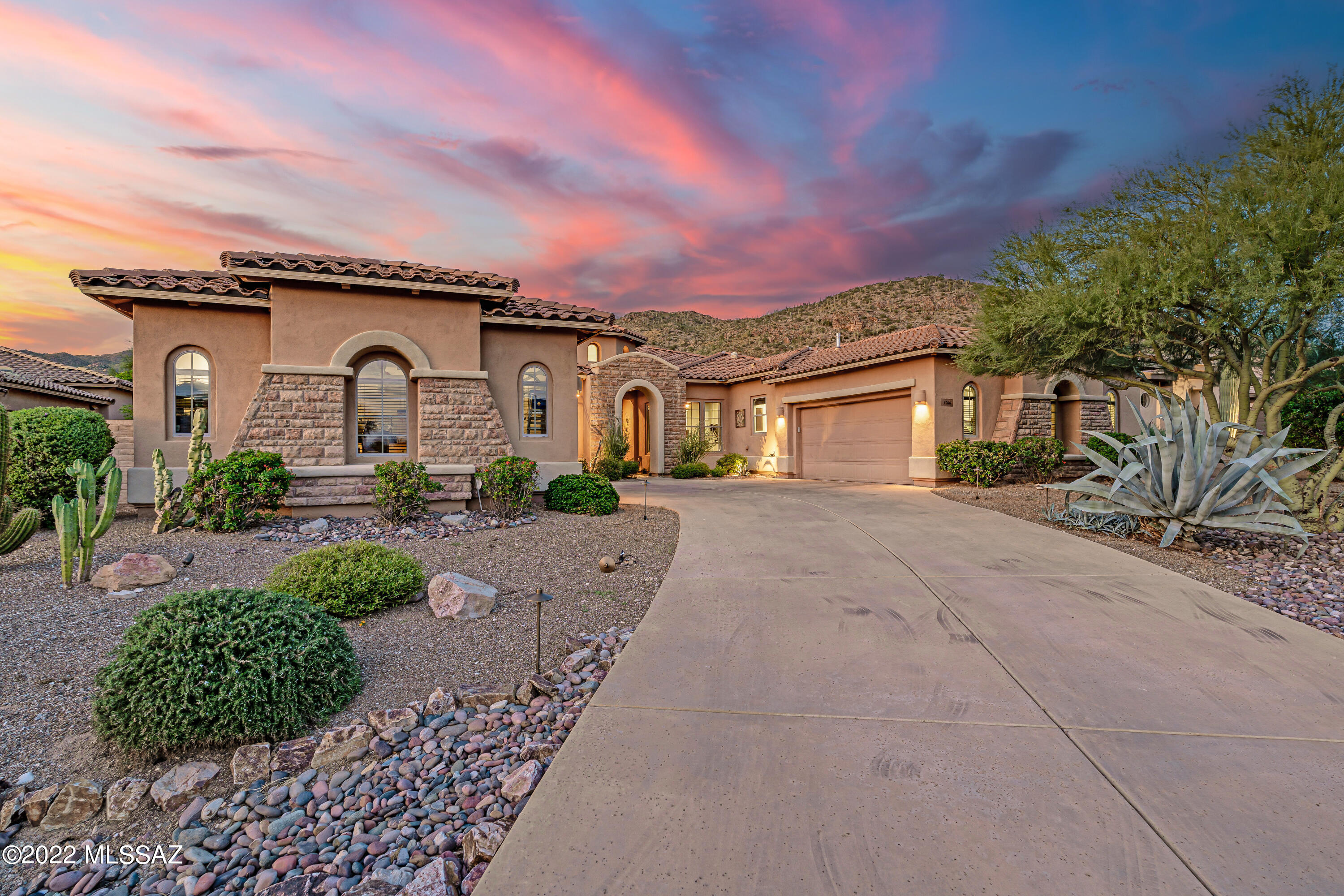 Immaculate 2006 Toll Brothers single story home privately situated in The Gallery at Dove Mountain's gated subdivision, Solana. Enjoy breathtaking mountain and sunset views on this private elevated lot. Front door opens to a grand circular foyer with clerestory windows and cathedral height ceiling. A true entertainer's delight, this tastefully upgraded home boasts a spacious great room with two living areas, a media space, and floor to ceiling stone glass fireplace. Remodeled dry bar features new granite, glass backsplash and wine/soda fridge. The stylish remodeled kitchen (within the last few years) showcases granite countertops, large center island with built in phone charging stations, glass tile backsplash, and high-end SS appliances including top-of-the-line 5-burner gas THERMADOR cooktop with downdraft, double wall ovens, built-in microwave, and single SS basin sink with a touchless pull-down sprayer. Sizable walk-in pantry. Skip the resort and experience the same luxurious amenities in your own backyard featuring an expansive covered patio, lush new turf, and Pebble Tec salt water pool with grotto, waterfall, slide, and baja shelf. Free-standing hot tub with LED lighting. Enjoy the gas fire-pit and BBQ area surrounded by mature desert landscaping and an abundance of delicious fruit trees including fig, sumo mandarin orange, pomegranate, and limequat! 
Expansive master suite complete with cozy sitting area, dramatic floor to ceiling gas fireplace, plantation shutters, and his & her walk-in closets. Luxurious ensuite bath featuring double vanities, oversized walk-in shower, jetted tub, separate dressing vanity, and private water closet with additional storage. Optimal split floorplan accommodates two-bedroom guest suite with private en-suite bath. Attached 2-car garage as well as detached 2-car garage perfect for the car enthusiast, studio, workshop, or home fitness area. Don't miss out on this beautiful Dove Mountain oasis!