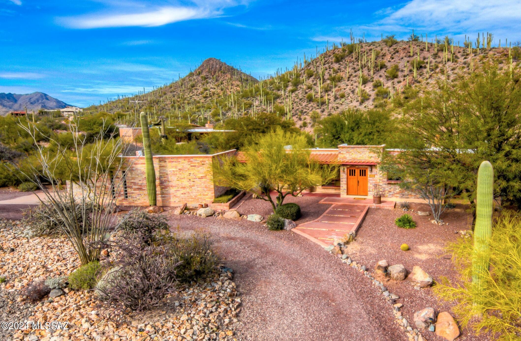 This private, tranquil hillside home is a true desert paradise. Bordering high desert Tucson Mountain Park land with saguaros in every direction. Rustic elegance - this is an upscale, fully remodeled burnt adobe. Quintessential desert southwest...exposed San Luis Adobe block interior/exterior walls, Mexican tile & desert vistas along w/ expansive outdoor covered paver patios & courtyards. Features: Open floor plan & chef's kitchen, 2 fire places, alum clad wood doors/windows & concrete finished 2 car garage w/ storage & wkshp. Incredible access to hiking, cycling, star gazing & desert wildlife. Walk to Gates Pass or Watson Peak Summit Trails with direct access to Saguaro National Park West. Around the corner to the Arizona-Sonora Desert Museum, Downtown Tucson, UA & Interstate 10