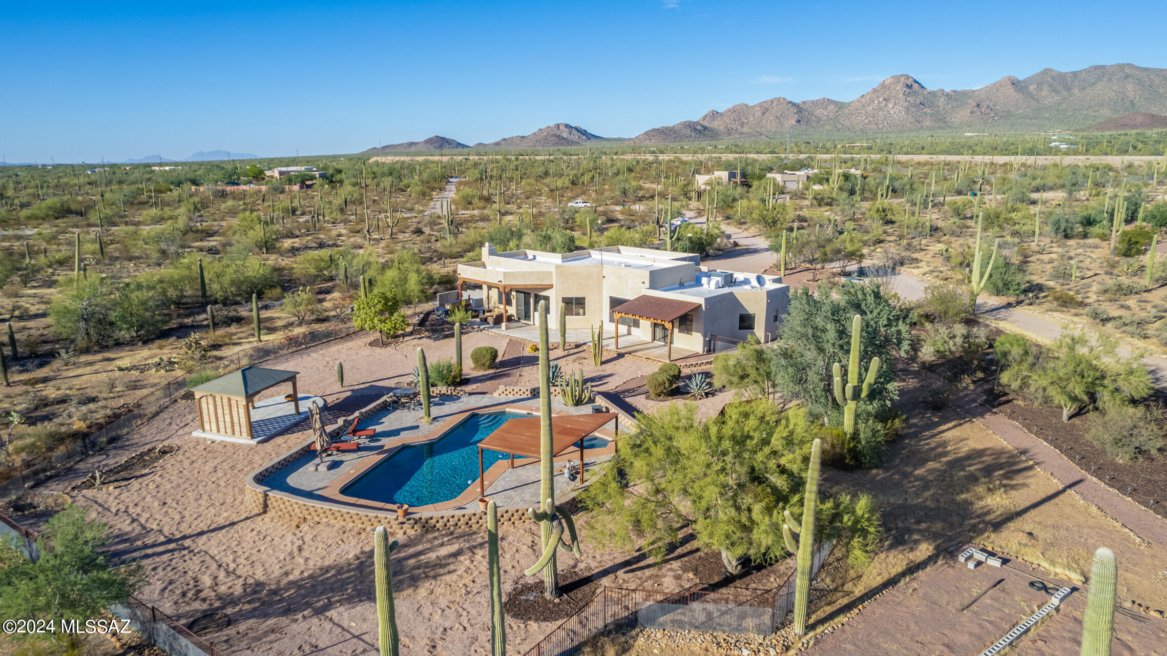 5+ acres, No HOA.  Discover desert living at its finest in this gorgeous custom-built Santa Fe-style home, complete with a 665 sq. ft. casita, situated on 5+ acres bordering Tucson Mountain Park and Saguaro National Park. Enjoy panoramic views of saguaros, lush desert vegetation, and stunning sunrises and sunsets. The main house welcomes you with high ceilings, large windows that bathe the home in natural light, and a cozy living area with a wood-burning kiva fireplace. The updated kitchen features granite countertops, stainless steel appliances, and opens to the living space with viga beams and an airy feel. The split floor plan includes a spacious master suite and bedroom/office on one side, with two guest bedrooms & a bath on the other, perfect for privacy or flexibility. with two covered patios, a charming brick courtyard, and a pool/spa area with a covered ramadaideal for year-round enjoyment. The detached casita, nestled just far enough for privacy, is perfect for an art studio, workshop, or guest house. It features concrete floors, a kiva fireplace, a kitchen with tile accents, a soaking tub, and its own laundry room. With uninterrupted desert and mountain views, this home is a private retreat where you can relax and connect with the natural beauty of the Southwest.