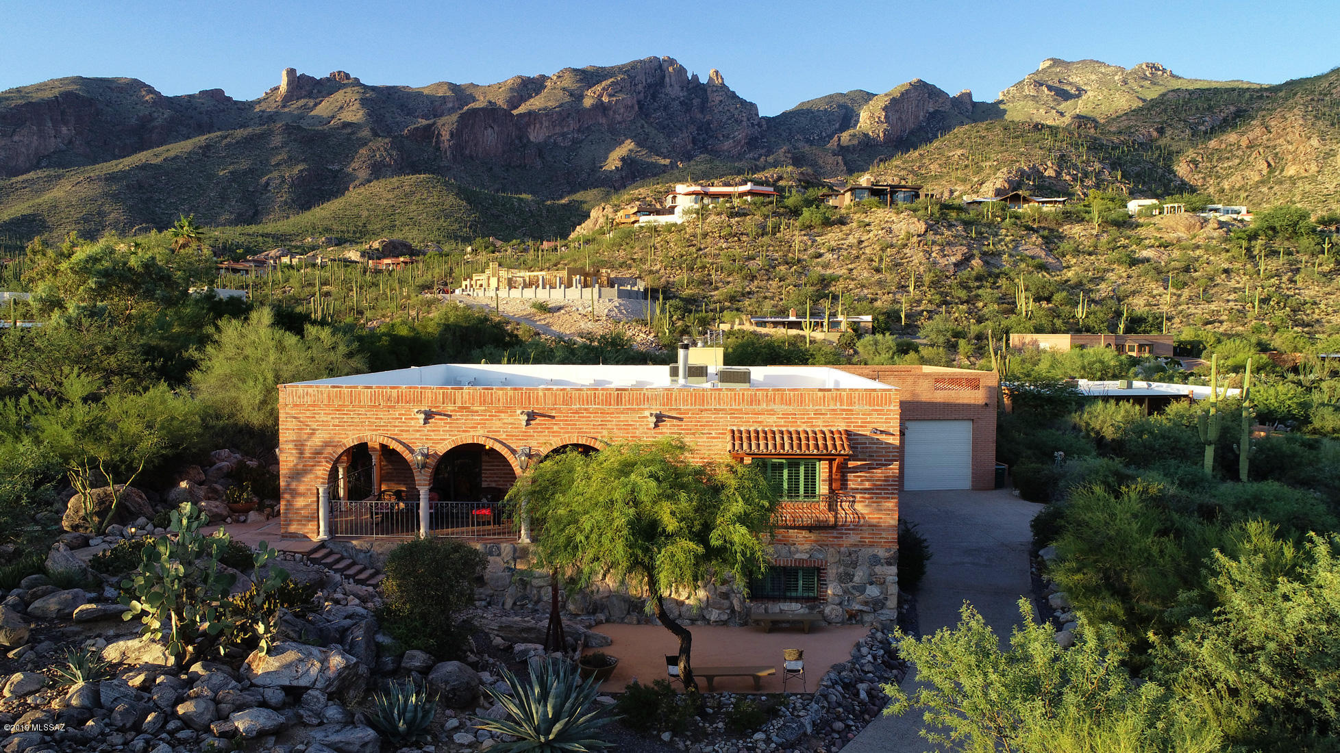 A stunning one-of-a-kind retreat perched high in the Catalina Foothills in the shadow of famed Finger Rock, with Old Tucson charm yet masterfully and tastefully updated, with the potential to be multi-generational or to accommodate a private practice with a separate entrance, is now available for your perusal. It's on a cul-de-sac with very little traffic, fabulous privacy and an opportunity for quiet enjoyment of nature. A welcoming front terrace is a delightful spot to relax and enjoy the views and lights of downtown Tucson. Enter into an open foyer with a glassed-in stairway to lower level, a bright and airy space that could accommodate a tall sculpture or mobile. With a unique floor plan, the two levels of this charming home provide multiple spots to live and gather. The entry level provides a full living area with kitchen, powder room, dining room, breakfast nook, living room, large master suite, guest room with en-suite bath, and a wonderful rear terrace with fireplace and reach-out- and-touch views of Finger Rock and the Catalinas. The lower level is fabulous, with another large master suite, two additional bedrooms, a den and office/study/ library area, a stunning wet bar and a 600-bottle wine cellar. On the entry level, be sure to look up to view the 9' tall handsomely beamed wormwood ceilings. And note the genuine hardwood flooring as well. 
The kitchen is stylishly updated with handsome Brazilian stone counters and stainless Kitchen Aid appliances including 2 convection ovens and a six burner gas stove. There is a prep sink in the island, pull-out features in lower cabinets, built-in tray and lid storage, and a terrific walk-in pantry. Leaded glass cabinet doors add extra charm. Enjoy breakfast or supper looking out to the gorgeously landscaped rear yard and up to Finger Rock and the other peaks of the Catalinas. Even an adjacent powder room has "OMG" views! The dining room is a warm and comfortable space with views of lush desert plantings, city lights and the distant mountains to the south, with a sliding glass door out to the entry terrace. The graciously large living room is focused on the handsome Canterra stone wood-burning fireplace which is one of many warm gathering spots. Double glass doors lead to the rear terrace with another welcoming fireplace, overlooking the gorgeously landscaped rear yard and with wrap-around stunning views of the Catalinas and the mountains of East Tucson. The upstairs master suite likewise opens to this terrace and also enjoys views toward the mountains of East Tucson. With a brick wall, richly shaded built-in bookshelves and entertainment center and a sitting area, it's a welcoming space. An en-suite second bedroom also enjoys a custom sink set in an antique-style bureau. 
Head down the polished wooden stairs to enjoy the lower level for the large open family room with polished brick floors and adjacent study/office space. French doors lead out to a lower level screened-in patio, or "Arizona Room" with cozy with another charming fireplace surrounded by custom tilework and direct access to the gardens and multiple sitting areas in the yard. A lap pool (with a motorized pool cover) with 4 "endless" jets for exercise is also in the yard.  Back inside, the generously sized wet bar with gorgeous glass tile top beckons. Beyond is the 600 bottle wine cellar, behind hermetically sealed glass doors, that won a design award from Sunset Magazine. It's lovely, elegantly lit and has room for a couple of bistro tables for wine tastings. What a spot to entertain! Nearby, a substantially sized 2nd master bedroom has handsome custom wood-framed glass doors out to the Arizona Room. The master bath for this suite is handsomely remodeled with travertine floors and travertine lining the glassed-in contemporary shower.  Sinks are set in attractive antique-style bureaus with marble tops. The oval soaking tub enjoys views across the Valley to the East Tucson mountains. A fourth bedroom features Saltillo tiles and accesses a full bath with glassed-in updated shower and another sink set in an antique style bureau, each one unique. A fifth  bedroom is presently outfitted as a "Closet For A Princess" with shelving, hanging space, a make-up table and its' own large walk-in closet; this space could be easily converted back into another bedroom. A large laundry room features an oversized stainless-steel utility sink. The rear yard features multiple sitting areas, one with a motorized shade and another inside a gazebo, and is a quiet private respite with only the sounds of the birds. There is an RV-capable garage (up to 31' RV) with an air-conditioned workshop, sink and loft, with an observation deck on top of the garage....wrap-around views of the entire Tucson Valley! Note the on-site parking for 3-4 vehicles, with stunning entry gardens leading up to the home. A couple of technical details: the exterior walls of the lower level are thick concrete block covered with fire brick so the downstairs stays cool...low electrical costs! Upper level and garage is adobe brick. There is a water pressure regulator and recirculating pump for the downstairs master shower. The upper deck is coated with an elastomeric coating that was professionally applied and will not be broken down by UV rays.  Dual zone Trane heat pumps with dual zone thermostats were recently installed.   Motorized pool cover keeps out debris and reduces costs for chemicals.  Of course, the location is "prime" with District 16 schools, easy access to the many amenities of the Foothills, and also to Tucson's excellent medical care. You are invited to come take a look, and to consider building your family's memories here as the current owners so enjoyed doing.