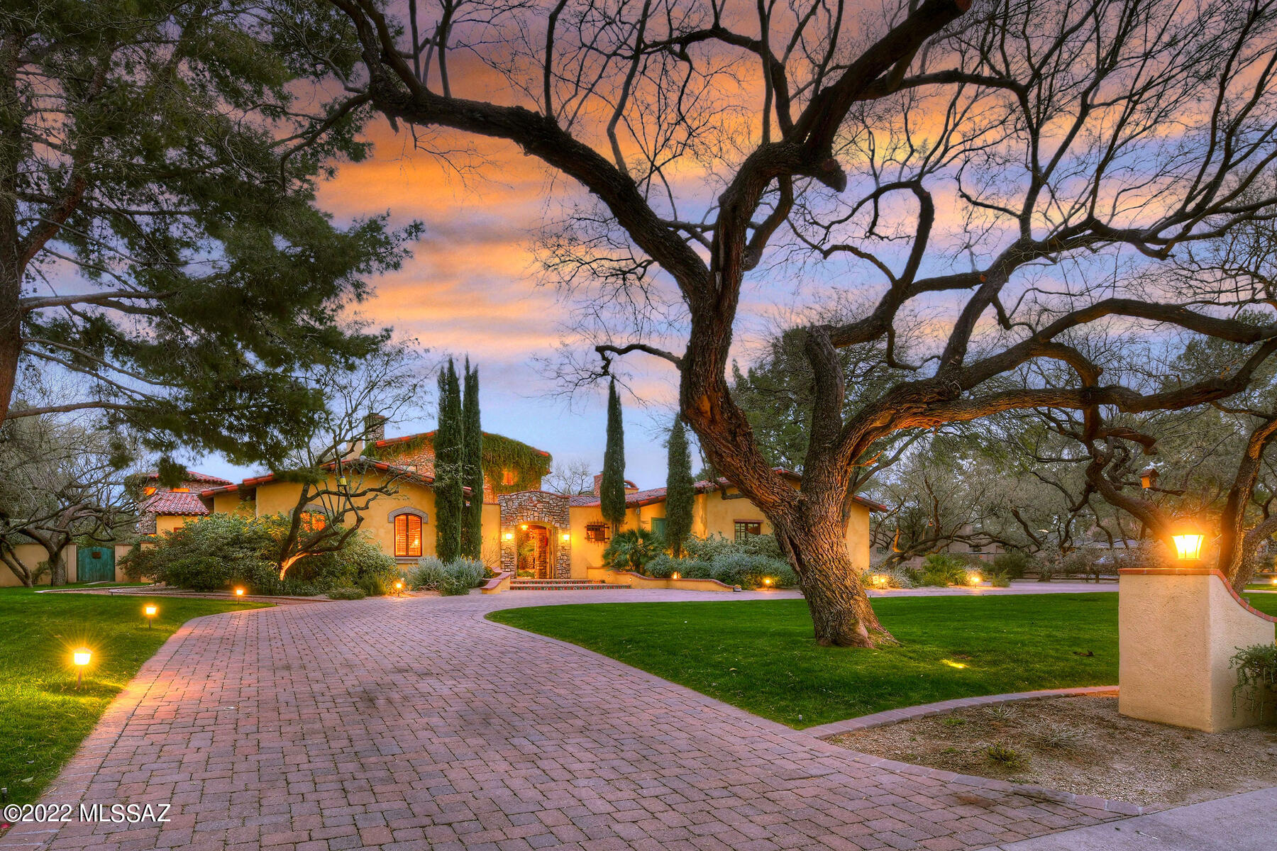 Presenting ''CASA DE ORO'' — This spectacular ''Old World'' Spanish Colonial-style masterpiece is nestled in guard-gated Tucson Country Club Estates and backs up to the 7th fairway of the golf course.  This stunning 5,414 sq. ft. home, built by Perry Mele, features curated materials imported from San Miguel de Allende and Oaxaca. Highlights include lush grounds with grass and majestic mesquite trees, hacienda-style courtyard entry with surrounding covered walkways, charming fountain and painted doors by artist Judy Perry.  Enter the main residence through vintage wooden ''speakeasy-style'' double doors into the great room featuring soaring 25' cathedral beamed ceiling, teak flooring, a grand gas/wood fireplace, "Tree of Life" hand-carved door, a full wet bar with refrigerator & 2 wine coolers, formal dining area, and hidden stairway leading to the 538 sq. ft. mezzanine/office.  Walk out of the mezzanine through double doors to the large roof-top terrace overlooking the golf course with sunrise and mountain views. The "pope's balcony" is perfect for sunset viewing.  Leading from the great room to the kitchen/family room is the butler's pantry, offering distressed cabinetry and glass doors. The fabulous gourmet island kitchen provides recessed Viking stove with stone surround, a wood-paneled refrigerator, double farm sink and arched ceiling. The family room, open to the kitchen, features teak wood flooring, cozy gas/wood fireplace, beamed ceiling, light & bright breakfast nook with high domed ceiling plus double-doors leading to the covered back patio with golf course views. The comfortable library/office/4th bedroom offers generous built-in bookcases, a charming gas/wood fireplace and an office alcove. From the great room to the master suite is the transition room (separating the public from the private areas) offering a vaulted ceiling with chandelier. The gracious master suite features scored concrete flooring, a coved beamed ceiling, a cozy gas/wood fireplace, 2 walk-in closets, and a sitting area. The luxurious en-suite master bathroom offers Mexican tile accents, dual vanities, a claw-foot tub in the circular "tub room", a steam shower, and a separate exercise room/office.  Bedroom 2 and 3 both provide en-suite baths. Bedroom 3 is perfect as guest quarters featuring a separate entrance off the courtyard plus a large closet with a small fridge & microwave. Walk out of the great room through double doors onto the 56' x 13' covered back patio complete with an outdoor gas/wood fireplace, ceiling fans, two chandeliers and brick flooring. Enjoy the beautiful backyard offering a generous grass area with mature mesquites, all backing up to the golf course.  Additional features include a vegetable garden, fruit trees, 3-car garage and an over-parking area.  Words and photos do not describe this residential masterpiece... see to appreciate!