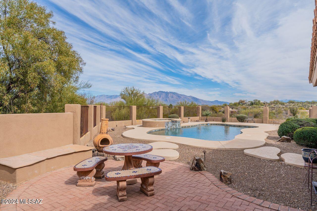 Sunrise to Sunset experience peace and serenity surrounded by sweeping mountain views and the beauty of the Sonoran Desert. If panoramic views are not enough,  enjoy evenings under the stars and the city lights of Tucson. Located in the Foothills of the Tucson Mountains, his elevated 3.42 acre cul de sac parcel offers privacy and space & yet is within minutes of downtown Tucson, University of Arizona, Tucson Mountain Reserve & the ''Loop'' for biking and hiking. Through the double door entry the Grand Foyer opens to a series of 4 arches leading to the open and spacious formal living room, dining room(now a billiards room) & family room which features slate fire place surround /hearth & slate entertainment center. The family room opens to kitchen & casual dining area. The wide central hall combined with generous living spaces, all neutral decor, high ceilings, abundance of windows(sited to capture mountain views)bring light and brightness to this comfortable smartly designed custom territorial home. This personal retreat is enhanced by the resort like side/back yard. By day enjoy pool/spa, rock water feature, outdoor BBQ, desert flora and fauna, fabulous mountain views...by night watch the city lights from the comfort of the covered patio! The unattached bonus building (600sqft) adjacent to patio provides multiple options: exercise room, workshop, home office, poolside rec room, or guest casita. There is NO HOA! So near yet seemingly so far away...this is a very special place to call home! You'll never want to leave!