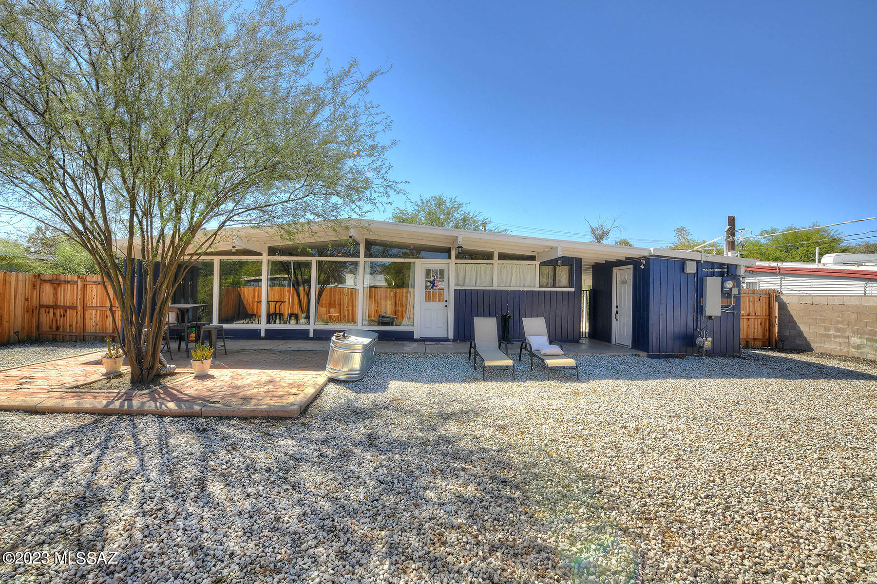 Tucked behind brand new metal security fencing w/electronic front entry gate you'll discover this absolutely charming  and recently remodeled mid-century gem!  Beautiful new flooring throughout, new luxe baths, new kitchen w/ss appliances & rich wood butcher block counters, new central HVAC, floor to ceiling windows that draw natural sun-dappled light into the cheerful main interior living spaces, new paint, and terrific yard space all around the home's perimeter.  Wonderfully inviting, a completely private sanctuary, and really, truly special in Central Tucson!