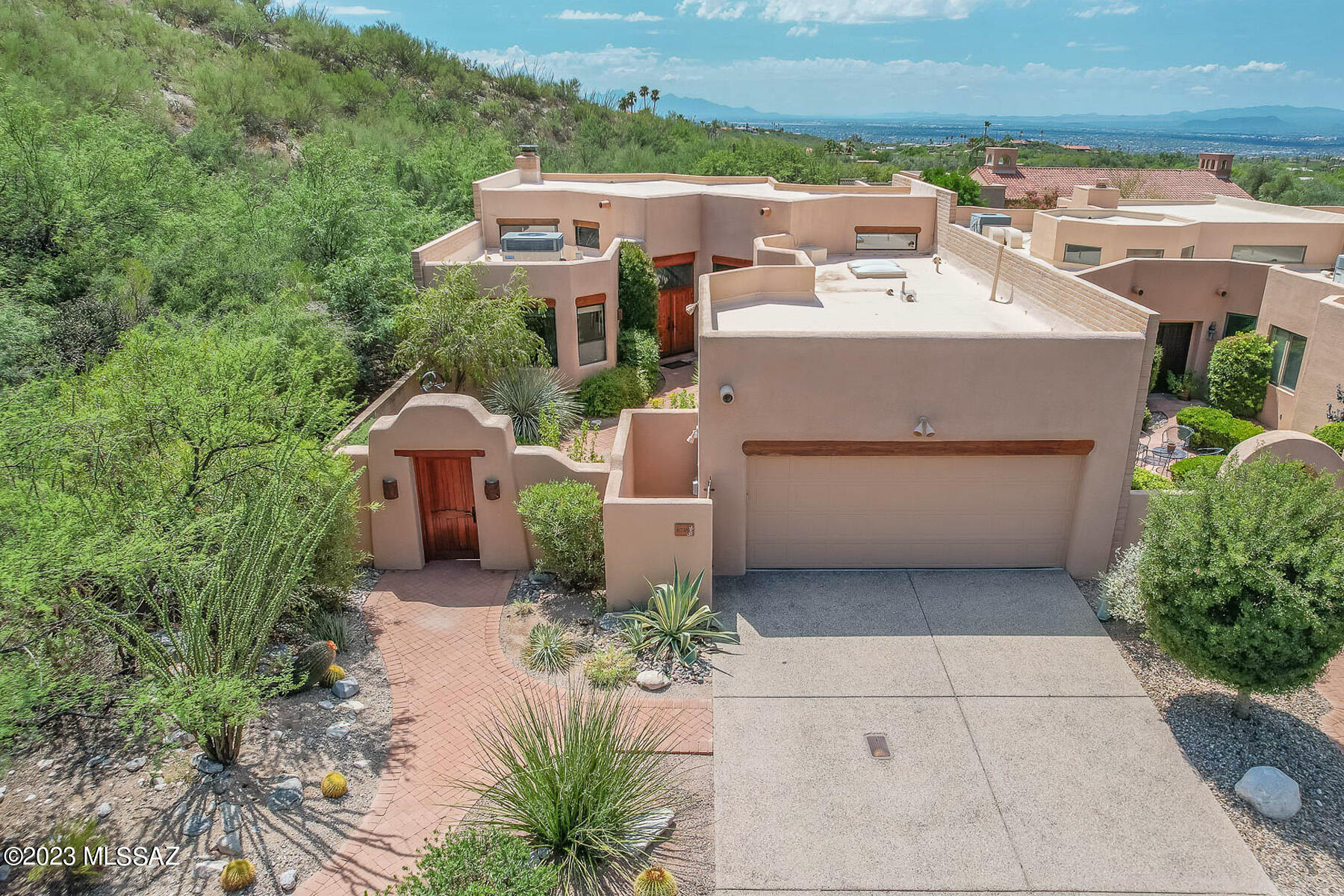 Welcome to this exceptional 2BR/2BA + den custom Santa Fe townhome, nestled on a serene end lot in sought after guard gated Finisterra Estates. The gated courtyard entrance, w/its high walls, creates a sense of the Old Pueblo, & leads to an open floor plan w/soaring 16' high plank/beamed ceilings, saltillo tile, solid core doors & expansive windows. The great room incl a wet bar, an entertainment center, a gas/wood burning beehive fireplace & built-in bancos under a large picture window that captures views of the saguaro studded mountains, natural desert & city. The sophisticated dining room incl a built-in buffet, an artistically  designed etched glass chandelier & is perfect for entertaining. A den/office w/built-in desk & bookshelves, incl a closet & could be used as 3rd BR. The light & bright kitchen has newer stainless steel appliances, decorative tiles, a center island, a built-in breakfast nook & large walk-in pantry. 
The spacious primary bedroom suite has 2 walk-in California closets & windows w/remote controlled rolling screens..
The primary bathroom has dual vanities, a jacuzzi tub, separate shower & a linen closet. The split bedroom plan incl a gracious guest bedroom w/built-in dresser & banco. The unique design of the backyard incorporates a ramada w/a new plank/beamed ceiling & a large brick patio & features a built-in BBQ, tiled counters for serving, professional landscaping & panoramic views.  The subdivision offers a community pool/spa, pickle ball & tennis courts & club house. The artistic design & attention to detail make this a very special property. Original owners. View now!