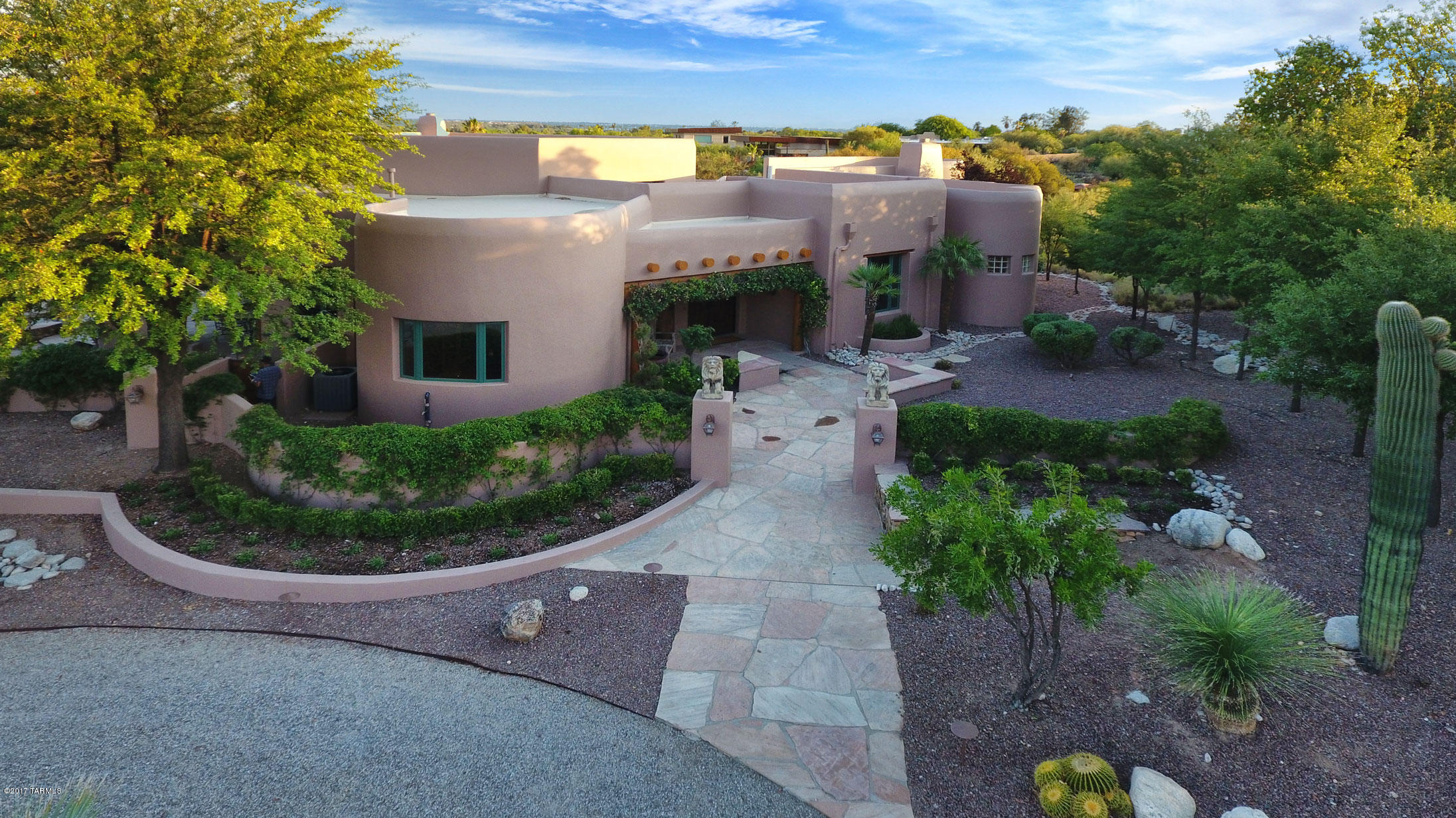 Welcome to an opportunity to reside in the renowned Tucson Canyon Ranch Wellness Resort in an unparalleled Southwestern Santa Fe style residence with fabulous upscale amenities in both the home and the community. The home provides the finest of construction and design details, and has recently been renovated and restored both inside and out at significant expense to be one of the most outstanding homes available in the area. Designed by highly respected and well known Tucson architect, Ron Robinette, in the Pueblo Revival style with a contemporary flair, the home’s thick walls, rounded features and extensive hand-hewn vigas, corbels, and latillos are balanced by soaring ceilings and a softly contemporary aesthetic expressed in exquisite materials, fabulous kitchen and bathroom elements, and glorious views from everywhere through an abundant utilization of tall windows and doors. 
The home incorporates many unique curved elements that provide a warmth to the spaces, as if the home were embracing you. The elegantly gracious entry foyer is topped with a handsome viga and latillo ceiling and opens to the living, kitchen, dining, bedroom and the office.  Handsome hand-carved lintels and corbels frame the entries to each area. The dramatic kitchen welcomes with a long oval island topped with gorgeous gleaming Italian Verde Grigio thick marble and an extensive matching curved wall of Verde Grigio marble counters and storage. Featuring the best of appliances, with a 6 burner + griddle Viking stove, Dacor wall ovens, Sub-Zero refrigerator, warming drawer, wine refrigerator, two sinks, pullout baskets and a large pantry, gourmet chefs or caterers would be quite comfortable here. A comfortable desk area includes a lighted curio cabinet that can display mineral or other collectables. The rounded northeasterly end of the kitchen provides a stunning direct view of the distinctive summit of Thimble Peak amidst the Santa Catalina Mountains, promising eye-opening sunrise views over morning coffee. The pentagonal dining room promises convivial intimate evenings under the beautifully double-coffered gracefully lit ceiling with a view to the outdoor terrace and warming kiva fireplace beyond. The salon, a warm gracious space for gathering and relaxing, is defined by its soaring ceilings and accented by a contemporary version of a traditional beehive fireplace, this one reaching to the 20 ft tall viga and latillo ceiling. Dramatically high clerestory windows abound for plenty of natural light. Glass doors lead outdoors to a long and deep traditional covered patio area with more richly carved and distressed corbels and lintels supporting the overhang, lovely irrigated gardens and mountain views in the distances. The curvature continues outdoors, with gracefully rounded outlines for the two levels of terraces and surrounding walls enclosing the home. A rustic stone waterfall enhances the sense of nature found in the warm materials utilized throughout.  Back inside, the powder room features Sherle Wagner gold-plated fixtures and accessories with a lovely sink set in an antique dresser topped in marble. The generously sized office looks out to more mountain views beyond the property's gardens, and has a handsome built-in bookcase hand-built by a local craftsman. Two ample guest bedrooms each have en suite baths and desert or garden views. The spacious master bedroom suite provides an oval wall of windows also overlooking desert views, and a gas fireplace set in a beautiful surround with a marble hearth. Look upward to the ceiling in this magnificent space, softly curved between whitewashed thick viga beams, a very unique and handsome feature. The real treat is the master bath, with exquisite Azul Blue Macauba Quartzite counters from Italy, creamy travertine marble floors, Jacuzzi tub surround and an oval travertine-lined shower. With more delightful views and a full make-up counter for the lady of the home, this is the spot for a glass of champagne while dressing for that special event, or relaxing in the Jacuzzi after a workout. And what a workout can be had, as Canyon Ranch has the most sophisticated array of exercise options imaginable, from the latest in equipment to the most amazing variety of classes guaranteed to help anyone accomplish their fitness and wellbeing goals. The Ranch and its affiliated Canyon Ranch Institute are famous world-wide for the creative and life-altering opportunities afforded to participants, from improving personal fitness and finding serenity, to recovering from traumatic injuries, to the development of healthy lifestyles. With over 400 fitness, educational and fun activities each week, plus the array of personal services available from a never-ending menu of massages, facials, purifying rituals, ayurvedic treatments and so much more, constantly updated, no one will ever tire of this cornucopia of choices. As a resident of the Ranch, these facilities are always available to you and your guests. Want a massage in the evening after dinner? No problem! Just slip  into your robe and walk over to the nearby Massage Center, afterwards take a dip in the beautiful private hot spa before slipping into sleep back at your own beautiful abode. These opportunities to own a home at the Ranch do not come often, and this home is one of those fabulous opportunities. We look forward to sharing it with you. A current appraisal for $3,000,000 is available upon request.