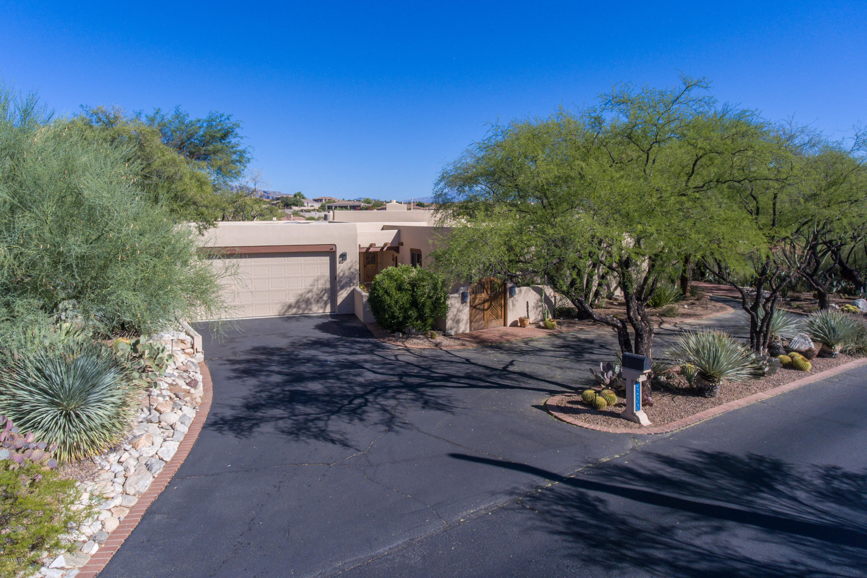 This Santa Fe is nestled in the heart of Catalina Foothills in desirable gated La Paloma. View beautiful changing colors & patterns of the Breathtaking Catalina Mountains from the north facing patio & living area.  Sit by the generous shady back patio or ramada & pool area to appreciate the city lights of Tucson & the lush Sonoran desert vegetation.  This home offers a split bedroom plan plus the guest bedroom has a separate bath.  Cozy den with more views next to the master suite with beehive fireplace.  Wood beamed ceilings. Saguaro ribbed gates. Dramatic North facing windows have remote controlled blinds.  Spacious  2 car garage  with extra storage & handy workshop.  Next to La Paloma Country Club, & convenient to La Encantada, Hiking & the University of Arizona. District 16 schools.