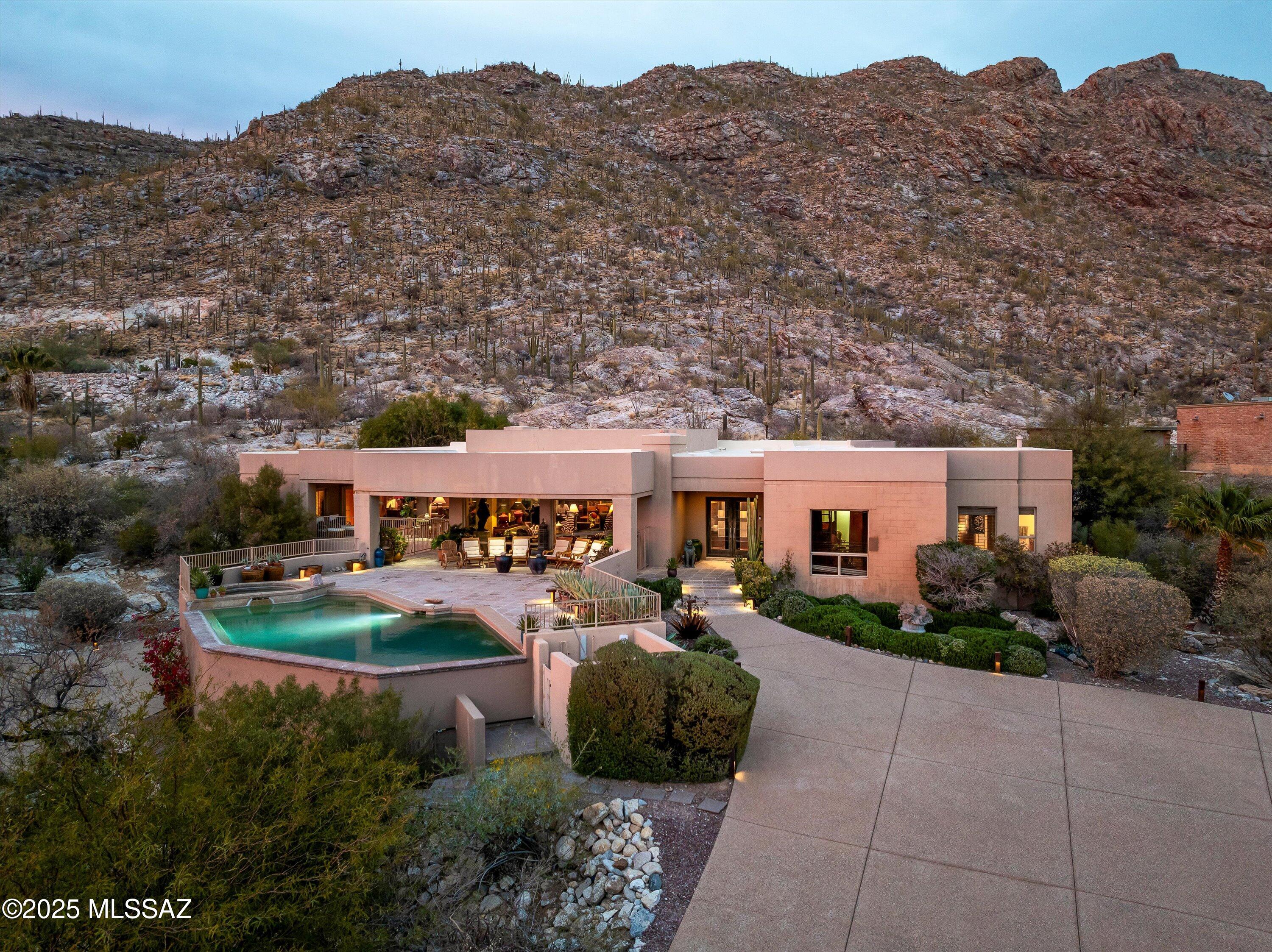 Perched majestically against the dramatic backdrop of Pontatoc Ridge in the exclusive Coronado Foothills Estates, this extraordinary 4,088 square foot residence transcends the ordinary concept of ''home'' to become something far more profound—a personal desert sanctuary where architectural brilliance meets untamed natural beauty.
Situated on 1.56 gated acres in the prestigious Catalina Foothills, this custom masterpiece represents the pinnacle of desert living, where each design element has been thoughtfully curated to honor both sophisticated comfort and the magnificent Sonoran landscape that surrounds it.
The residence is defined by its harmonious dialogue with the environment. Strategically placed oversized windows function as living canvases, transforming each room into a gallery where light, shadow, and panoramic vistas become integral design elements. Constructed with enduring solid block and adorned with custom Sonoran mesquite hardwood floors and elegant travertine, the home embraces both refinement and authenticity. The hallway, great room, and master bedroom suite feature exquisite Imperial Plaster walls, adding a subtle richness and texture that complements the architectural significance of the space.
The culinary sanctuary reflects global sophistication, featuring a professional-grade Thermador range, premium appliances, artisan cabinetry, and an island perfectly positioned for both serious cooking and social gatherings. As the heart of the home, this space is designed for creating memorable evenings against the backdrop of mountain views so captivating they rival fine art.
Retreat to the primary suitea sanctuary within the sanctuaryfeaturing dual luxury bathrooms, a supersized custom walk-in closet, and floor-to-ceiling windows that frame the ever-changing desert tableau. Two additional sophisticated bedrooms share an elegantly appointed bath, providing sumptuous accommodations for family or guests.
Step outside to discover a private resort-caliber environment where the heated infinity-edge pool and spa invite both refreshment and reflection. Multiple entertainment zones offer perfect settings for morning coffee amid visiting wildlife, afternoon dips in the shimmering pool, and evenings enjoying spectacular sunset views across the Tucson Valley.
What truly distinguishes this property is its extraordinary connection to the natural world. A custom water feature at the property's edge creates a serene oasis that attracts the region's remarkable wildlife. Desert bighorn sheep, native to the adjacent ridge, regularly visit this water sourceoffering residents the rare privilege of observing these majestic creatures from the comfort of home. The thoughtfully designed landscape includes additional water elements that blend seamlessly with native terrain, creating a harmonious transition between cultivated grounds and the wild beauty of the Sonoran Desert.
This rare offering includes thoughtful amenities that elevate everyday living: a private elevator connecting the main residence to the garage, two distinctive fireplaces, and exceptional privacy provided by both natural topography and secure gated entry.
More than a luxury residence, this property represents an invitation to extraordinary livingan opportunity to become the next steward of a home that celebrates the profound connection between sophisticated design and the untamed beauty of the Sonoran Desert. For those who recognize that true luxury lies in authenticity, privacy, and the daily celebration of natural beauty, 4361 E La Paloma Drive awaits.
Properties of this caliber and location rarely become availablea private viewing is strongly recommended, as this extraordinary desert sanctuary will not remain on the market for long