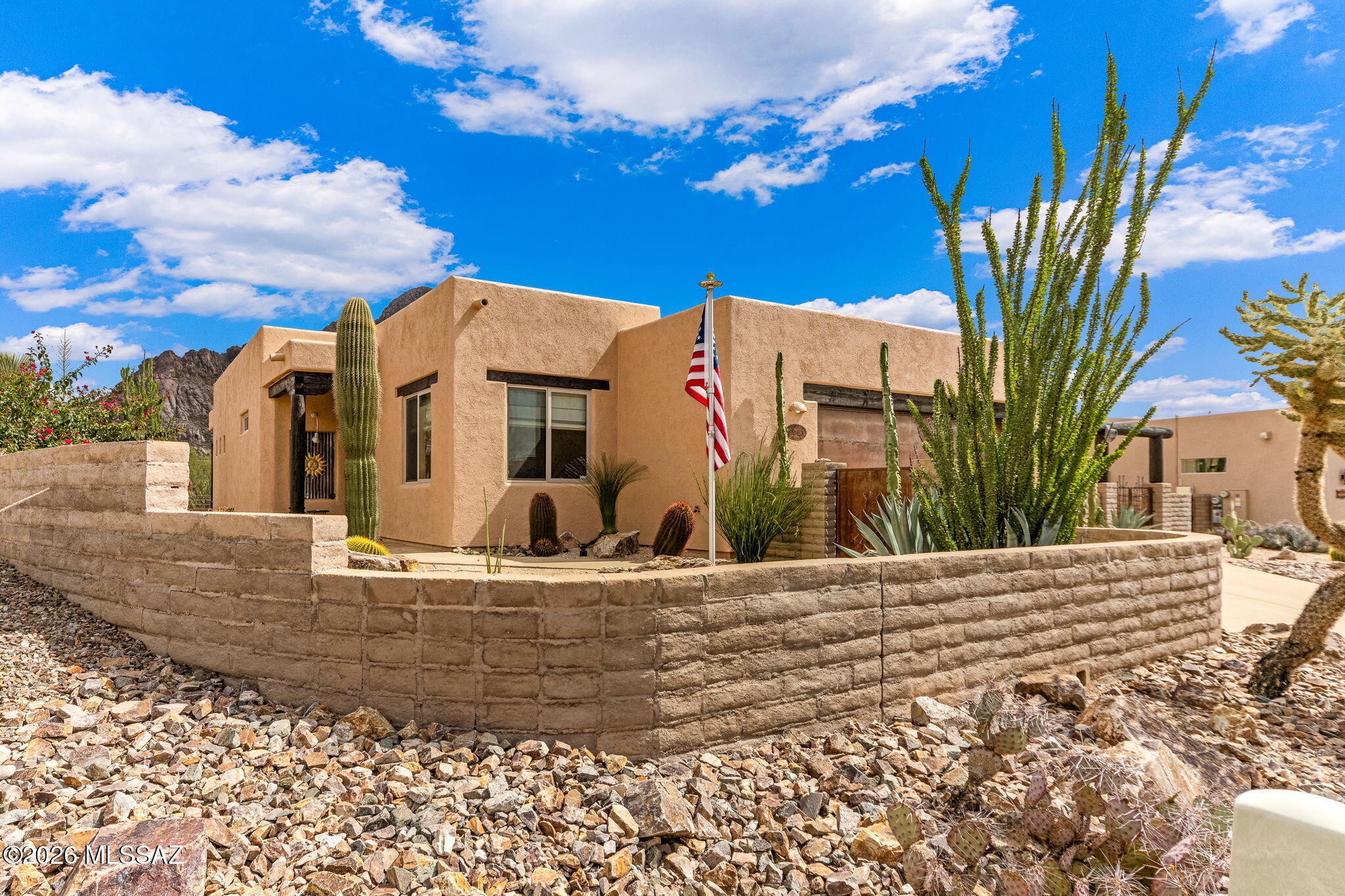 Nestled in the Tucson Mountains you'll find this rare Santa Fe gem built &  designed by John Herder. A true quality home located on .25 acre quiet and peaceful cut-de sac. Home offers architectural characters/custom artistic details every turn.Beams, high ceilings,gas beehive fireplace, unique niches, picture windows, custom knotty elder cabinetry and doors throughout.  Great room opens to kitchen w/many classes Sante Fe details. Primary bedroom retreat w/primary bath featuring dual vanities, seperate walk-in shower, walk-in closet & sliding glass doors to back patio. Home has been freshly painted & new gas water heater in 2025. Seperate laundry room w/cabintry, W&D. Backyard backs to private wash & mountain views. Must see home in person~photos cannot capture the uniqueness of this home.