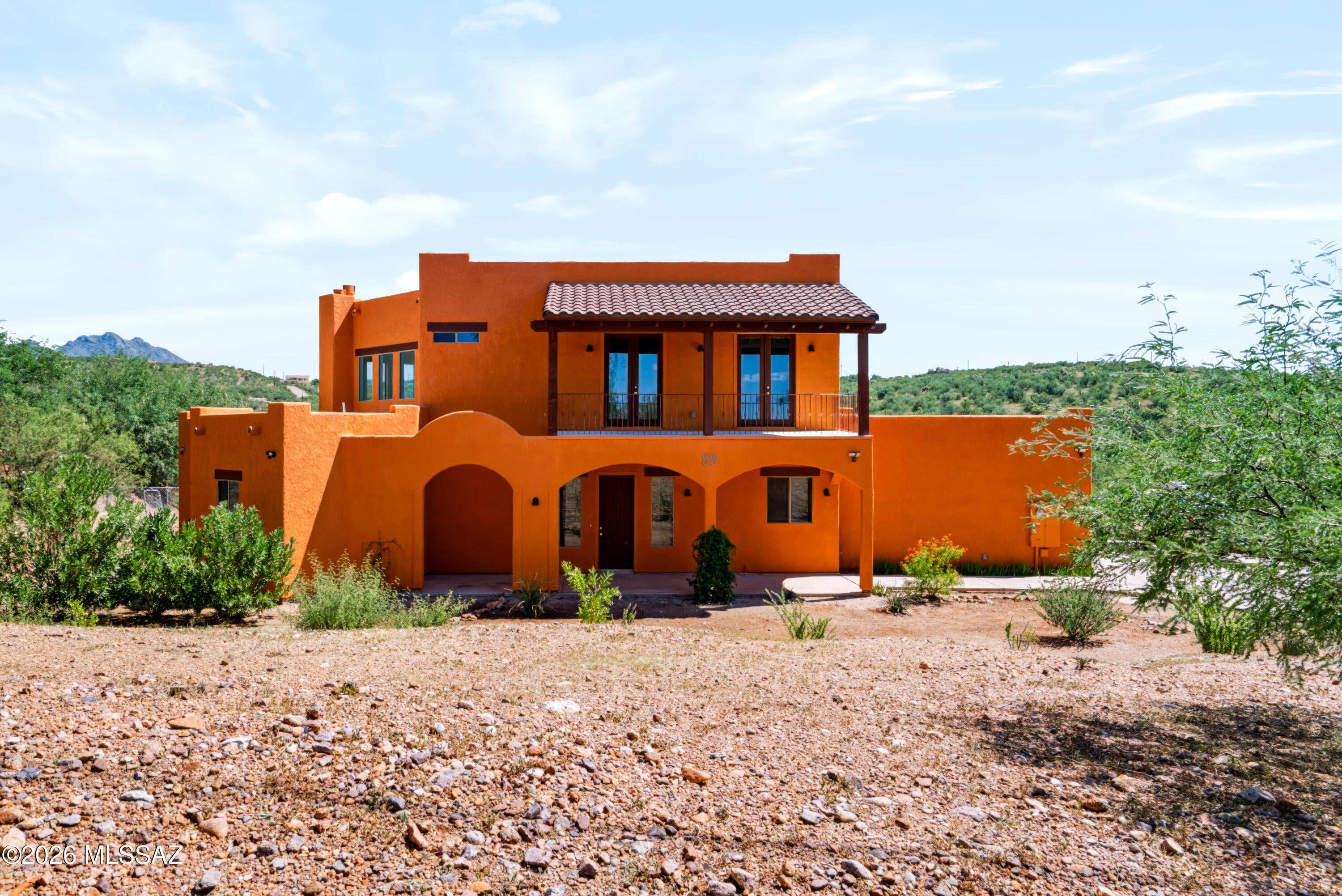 Welcome to this beautiful Santa Fe style home offering 3,151 sq ft of thoughtfully designed living space, featuring 4 spacious bedrooms and 3.5 bathrooms. The inviting open-concept floor plan seamlessly connects the living room, dining area, and family room, creating an ideal setting for everyday living and entertaining. The wood-burning fireplaces add warmth, character, and timeless Southwestern charm. The well equipped kitchen features granite countertops, a large island, custom cabinetry, and stainless-steel appliances, providing both functionality and style. The generously sized primary suite offers its own fireplace, a large bathroom, walk-in closet, and private access to the covered back patio perfect for enjoying peaceful mornings or relaxing evenings. The additional bedrooms are exceptionally spacious, with private bathrooms and access to their own upstairs balconies, creating comfortable and versatile spaces for family and guests. Step outside and take in the breathtaking views, with spectacular opportunities to enjoy both sunrise and sunset from your own property.The fully fenced, highly usable flat lot is beautifully complemented by low-care landscaping and decorative rock, offering an easy-care outdoor setting with plenty of room to enjoy. Located in Rio Rico, this distinctive Southwestern home combines character, comfort, generous living spaces, and stunning desert scenery. A wonderful opportunity to enjoy the beauty and lifestyle of Southern Arizona!