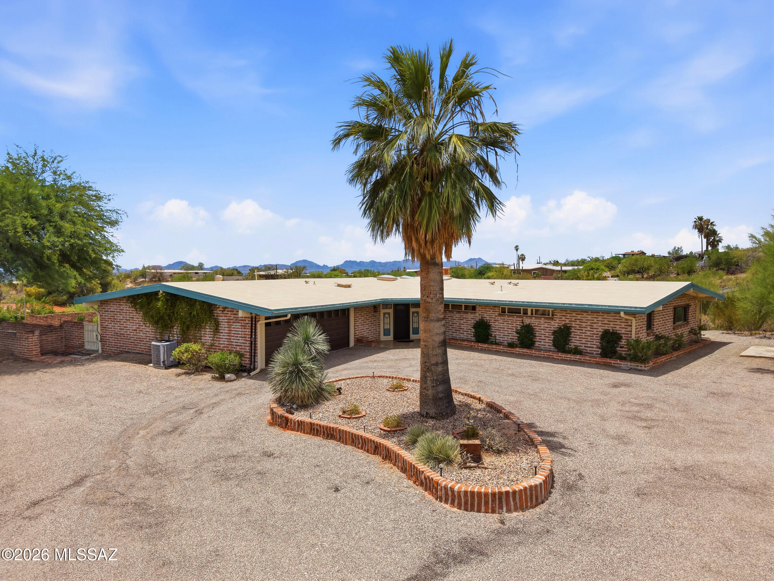 Spectacular Catalina Mountain and City Views are just the beginning for this rare find. This timeless 2940 sqft Burnt Adobe Ranch Style Home in Flecha Caida Ranch Estates was built in 1958 and features 3 spacious bedrooms 3 baths, one of which has an outside entrance from the pool/deck area. The living area is built to entertain, providing the opportunity to invite family & friends to enjoy incredible views inside or outside of the home. The Family Room extends to the Patio and Pool area thru two over-sized, double-paned sliding glass doors providing an extended Living area. The Dramatic Great Room features soaring beamed ceilings and over-sized double-paned windows in the living & dining area. You will be in awe of the natural stone wood burning FP in the living area. A rare feature in the hallway includes an original floor to ceiling walk-in Cedar Closet.
The recently upgraded kitchen is illuminated by 2 Sky Lights in natural wood beamed ceiling. An expansive kitchen counter connects the kitchen to the Dining Area as well as to the Family Room.
The grounds outside have 2.37  private acres that provide tranquility and privacy. A covered patio overlooks a sparkling solar heated pool framed by the mountains and offers fantastic sunrise/sunset view. The West Patio offers beautiful views of the Catalina Mountains, a Putting Green, a hot tub that can be accessed from the 3 bedrooms and the Great Room. An energy efficient drip irrigation system surrounds the home to easily maintain the landscaped area. A large 2 car attached garage features a workshop area and ample storage.