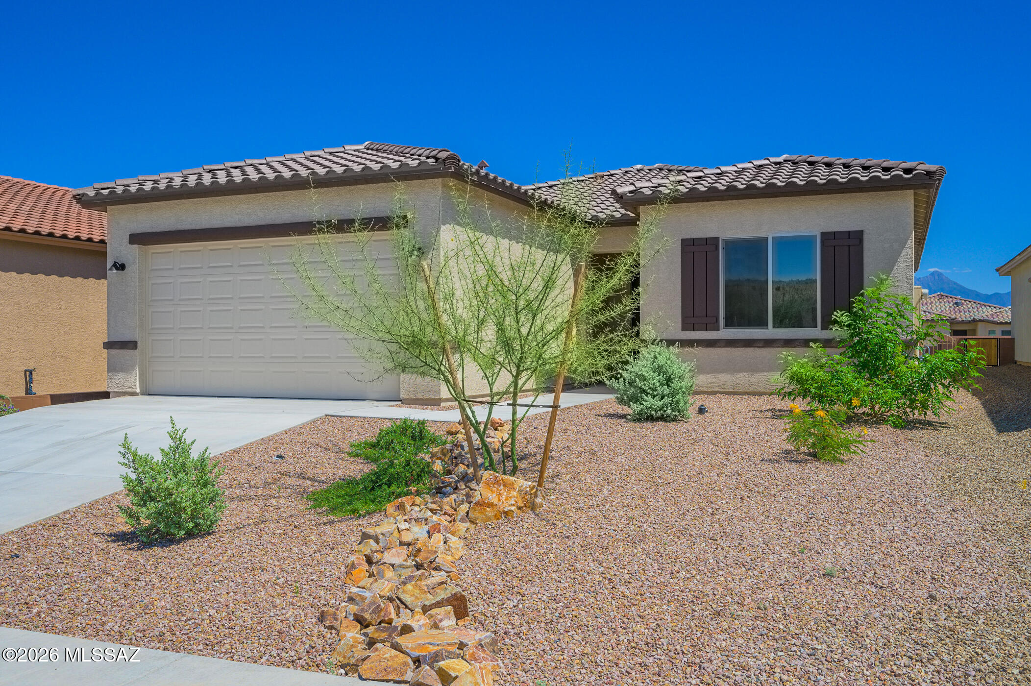 Discover your perfect Arizona retirement lifestyle in this beautifully crafted, new home by Fairfield Homes! Be the very first to enjoy every modern feature and finish, plus the peace of mind that comes with included builder warranties. Step inside and feel the welcoming openness created by wood-look plank tile flooring flowing seamlessly through the main living areas and den, with cozy carpet adding comfort in the two bedrooms.  The heart of the home is a stunning kitchen, expertly designed for both functionality and style. Enjoy elegant Mocha tone 42'' cabinetry, gorgeous granite countertops, and a striking geometric tile backsplash, all complemented by sleek stainless steel appliances--ideal for preparing your favorite meals and entertaining guests. A set of double French doors reveals  versatile den or home office, providing the perfect spot for hobbies or quiet reflection. The spacious primary suite features a charming bay window that brings in natural light and adds a touch of luxury. Step into your private ensuite bath, showcasing a dual-sink vanity and a sophisticated tile shower.  This move-in-ready home also includes access to the renowned Green Valley Recreation amenities--so you can spend your days swimming, playing pickleball, or joining a variety of clubs and social events. Whether you're seeking adventure or relaxation, this home offers it all in a vibrant, active-adult community. Don't miss this rare opportunity to own a never-lived-in residence designed for the next chapter of your life!