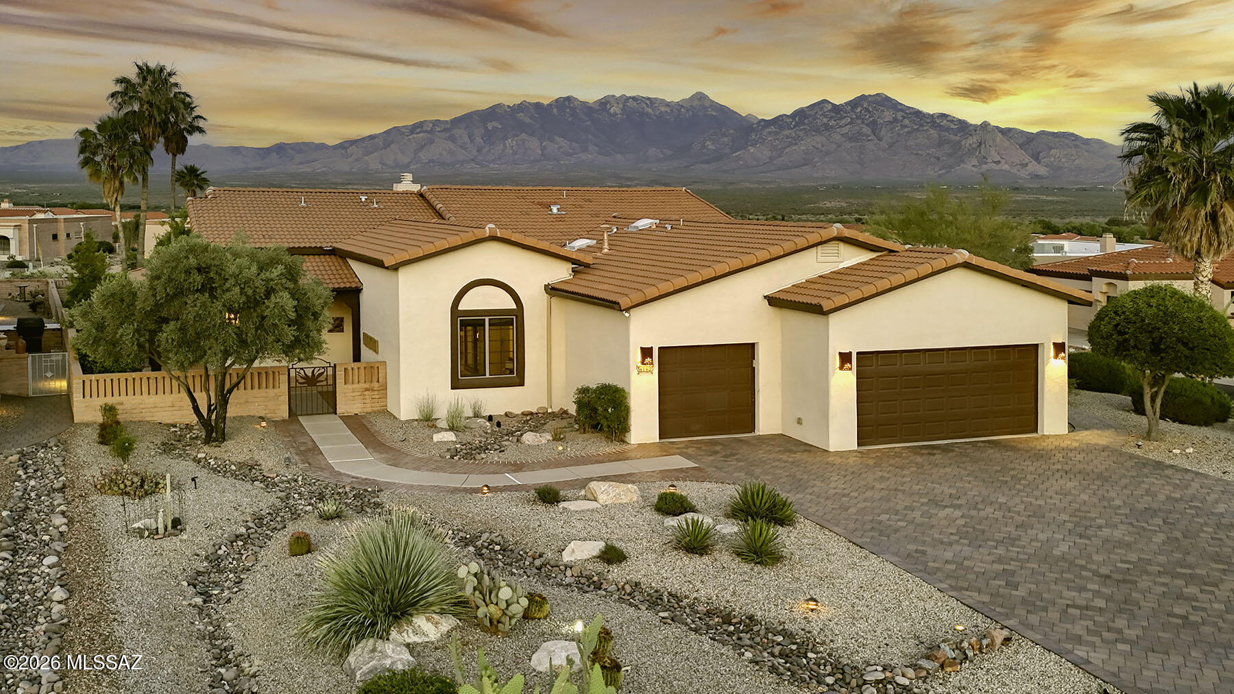 For the homeowner who demands the very best -- where breathtaking VIEWS and resort-caliber outdoor living converge -this exquisitely customized home in San Ignacio Heights stands in a class entirely its own. This is not simply a home; it is a lifestyle destination, and arguably the crown jewel of the neighborhood.  
From the moment you arrive, the attention to detail is unmistakable. The red brick-paved driveway makes a lasting first impression, and draws you naturally toward the charming front courtyard -- a private, sun-drenched sanctuary enclosed for maximum privacy.  The interior of the home reveals itself with drama and grace.  Soaring ceilings, raised to an impressive 15 feet in the great room, create an immediate sense of volume and grandeur rarely found. An impressive bee-hive fireplace creates a natural gathering spot.  Sun light pours through oversized, custom wooden-framed Anderson sliding glass doors. These sliders frame the surrounding mountain panorama like living artwork, ensuring the views are a constant, breathtaking presence throughout daily life.  The kitchen is nothing short of spectacular.  Rich cabinetry, large double door pantry, a new refrigerator,  stainless 5 burner gas cook-top with stainless exhaust hood, new convection/air fryer oven and microwave oven, and gorgeous new granite on counters and center island!   A breakfast nook is adjacent and is conveniently located by the outdoor kitchen and pergola.  The great room flows seamlessly into dining and kitchen spaces, maintaining the open, airy character of the floor plan while offering the kind of functionality that suits both everyday living and elevated entertaining.  A separate formal dining area is open to the living spaces and features a lighted coffered ceiling that adds ambience and warmth to the room.  A lovely den can be used as a media room, office or guest overflow. Your guest ensuite is perfect for long term guests.  The primary suite in the home offers the luxury and space you have yearned for.  Wake up in the morning to the beautiful Santa Rita Mountain views.  Step out to the patio in the evening to gaze at the stars.  Take a soak in the oversized tub, or enjoy your spacious walk-in closet.  
It is outside, however, where this property truly transcends expectation. This is an outdoor living environment of rare beauty and sophistication, where panoramic mountain views serve as the permanent, ever-changing backdrop to a life lived largely al fresco. The outdoor living areas themselves are generous and multi-functional.  Covered patio spaces extend the interior square footage into the open air, offering shade, comfort, and an ideal setting for outdoor dining, lounging, and entertaining. An extended lot and a brand new outdoor kitchen complete the resort like feel.  Whether hosting an intimate dinner under the stars or a larger gathering with family and friends, the outdoor spaces accommodate every occasion with ease and elegance. This is a home for someone who has considered what they truly want from the place they live -- and has found it. Views without compromise. Outdoor living without equal. Interior finishes without parallel. If that is the life you are seeking, this special home in San Ignacio Heights is waiting for you.