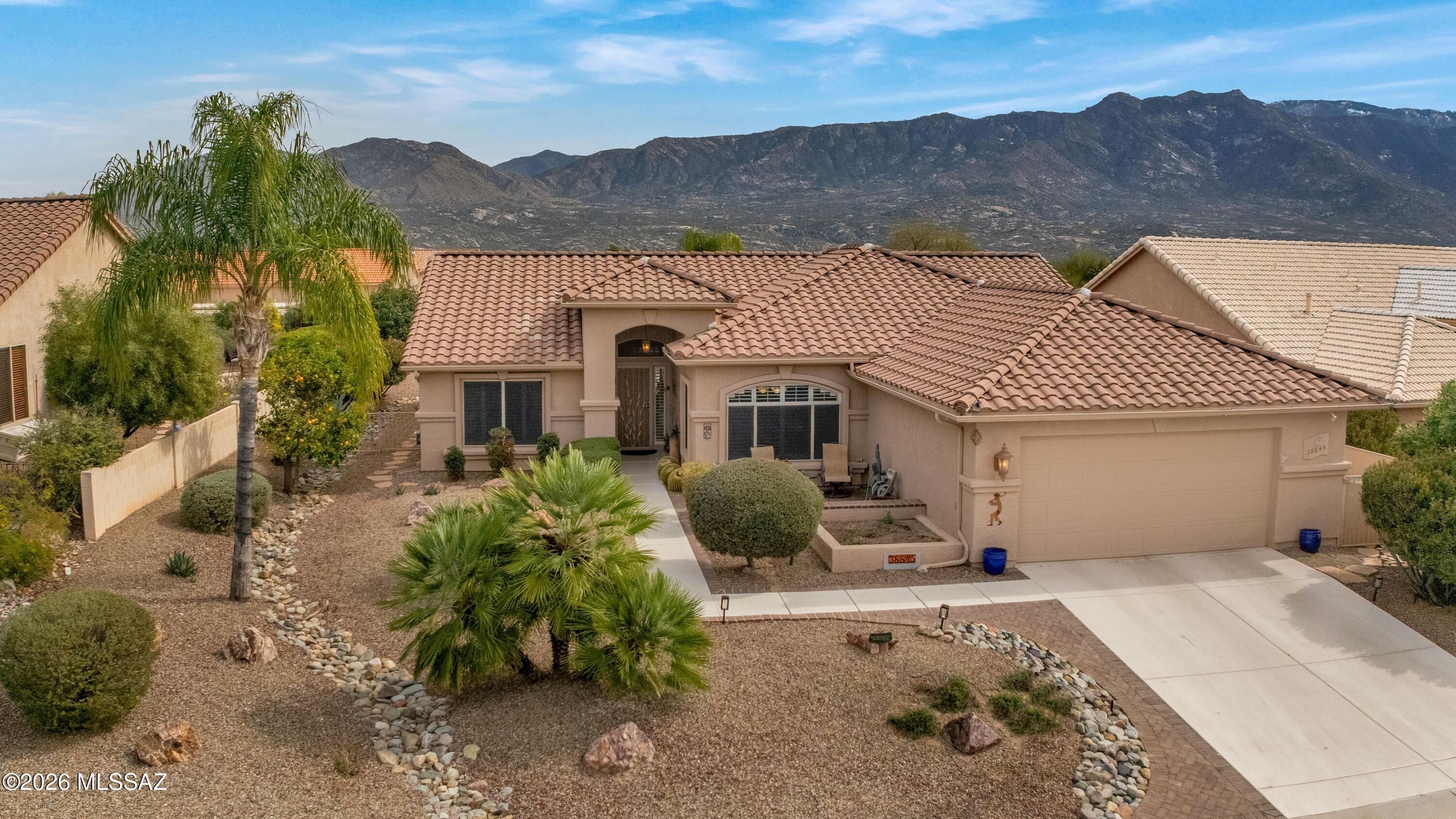 Expanded Laredo with Mountain Views! Roof underlayment & irrigation system replaced in 2023. Extended 2-car garage with 2020 HVAC, 2025 W/H, sink, cabinets, & epoxy floor. Welcoming front courtyard. Spacious great room features built-in entertainment wall & slider to patio. Kitchen offers granite counters, black stainless appliances, cabinets with slide-outs, island, & dining area. Owner's suite with bay window. En Suite Bathroom has walk-in shower, & walk-in closet. Den/office with French doors. Guest bedroom with closet & nearby guest bath. Laundry room with W/D, pantry, & cabinets. Whole-house water filtration system. Luxury vinyl plank flooring in great room, den & owner's suite.  Covered patio, built-in BBQ, water fountain, lovely landscaping, lemon tree, gated yard, & mountain views!