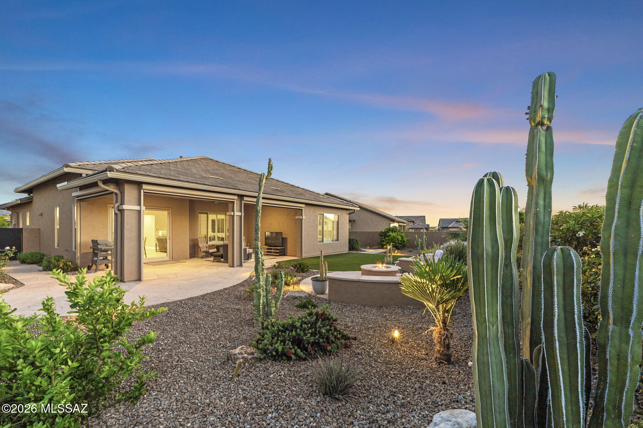 Better than new construction, this upgraded Alora model, which can be purchased with most furnishings has been impeccably cared for and sits on an expansive .21-acre lot. Surrounded by lush desert flora, vibrant cacti, and citrus trees, the backyard features a dedicated gas firepit perfect for soaking in the Arizona sunsets. The fully fenced yard and generous side pathways offer ample space for gardening and seamless movement around the property.  Inside, the functional layout includes 2 bedrooms plus a den, 2.5 bathrooms, and an oversized 2.5-car garage. Recent improvements include professionally painted exterior, fresh interior paint throughout the main living areas, new decorative landscaping rock, automated landscape lighting, and a whole-house surge protector.

Specialized upgrades elevate the home, featuring a custom entry door that floods the space with natural light and motorized solar shades that instantly transform the back patio into a fully enclosed Arizona Room.

Perfectly situated for an active lifestyle, this home is near the heart of the community. Residents enjoy immediate access to a comprehensive suite of amenities, including the 18-hole championship golf course and clubhouse. Whether you're visiting the state-of-the-art fitness center, relaxing by the resort-style pools, or meeting friends at the pickleball, tennis, and bocce courts, everything is within easy reach. The community also features creative arts studios, gardens, a dog park, and scenic nature trails, ensuring a vibrant lifestyle just steps from your front door.