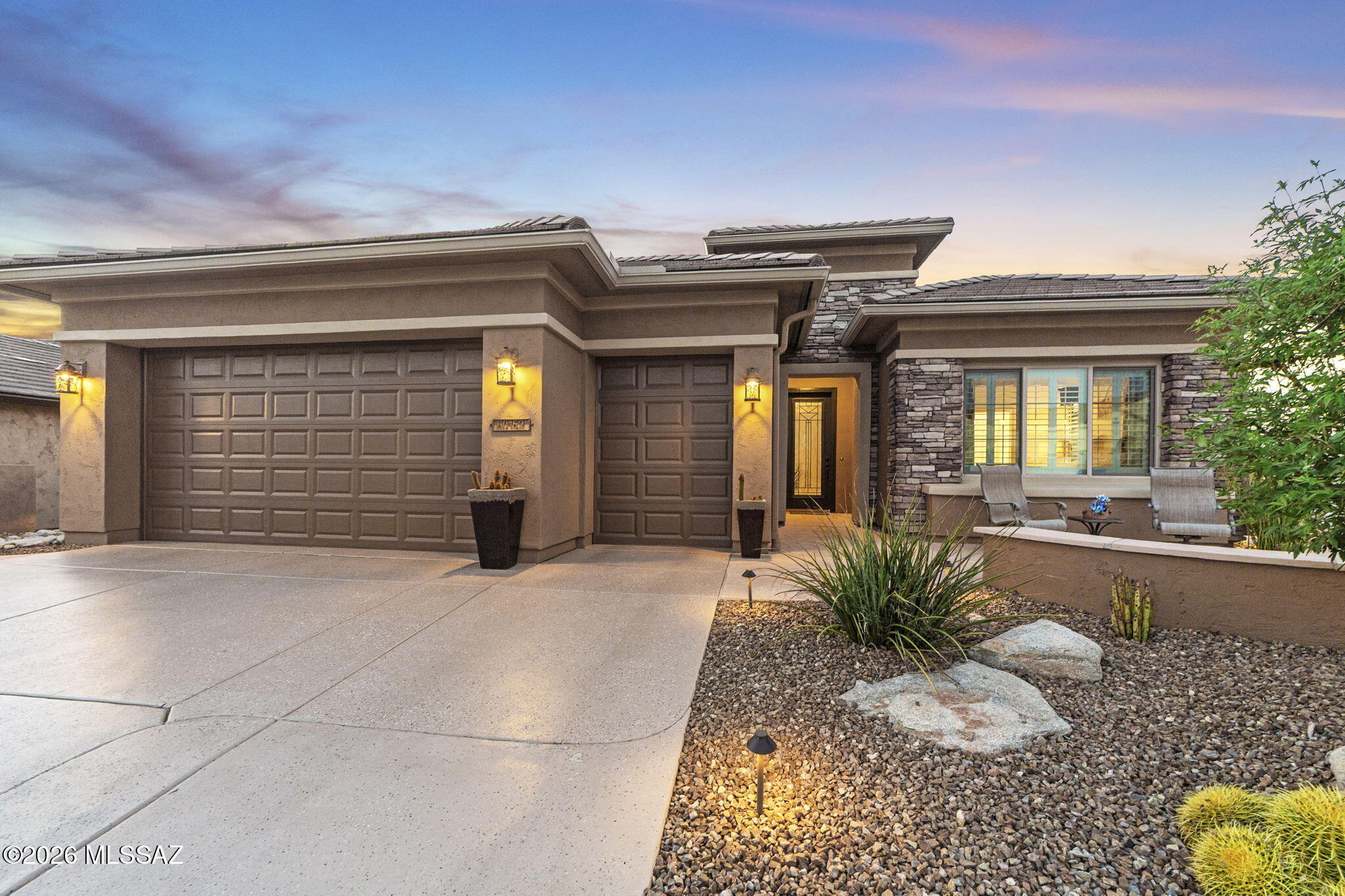 Better than new construction, this upgraded Alora model, which can be purchased with most furnishings has been impeccably cared for and sits on an expansive .21-acre lot. Surrounded by lush desert flora, vibrant cacti, and citrus trees, the backyard features a dedicated gas firepit perfect for soaking in the Arizona sunsets. The fully fenced yard and generous side pathways offer ample space for gardening and seamless movement around the property.  Inside, the functional layout includes 2 bedrooms plus a den, 2.5 bathrooms, and an oversized 2.5-car garage. Recent improvements include professionally painted exterior, fresh interior paint throughout the main living areas, new decorative landscaping rock, automated landscape lighting, and a whole-house surge protector.

Specialized upgrades elevate the home, featuring a custom entry door that floods the space with natural light and motorized solar shades that instantly transform the back patio into a fully enclosed Arizona Room.

Perfectly situated for an active lifestyle, this home is near the heart of the community. Residents enjoy immediate access to a comprehensive suite of amenities, including the 18-hole championship golf course and clubhouse. Whether you're visiting the state-of-the-art fitness center, relaxing by the resort-style pools, or meeting friends at the pickleball, tennis, and bocce courts, everything is within easy reach. The community also features creative arts studios, gardens, a dog park, and scenic nature trails, ensuring a vibrant lifestyle just steps from your front door.