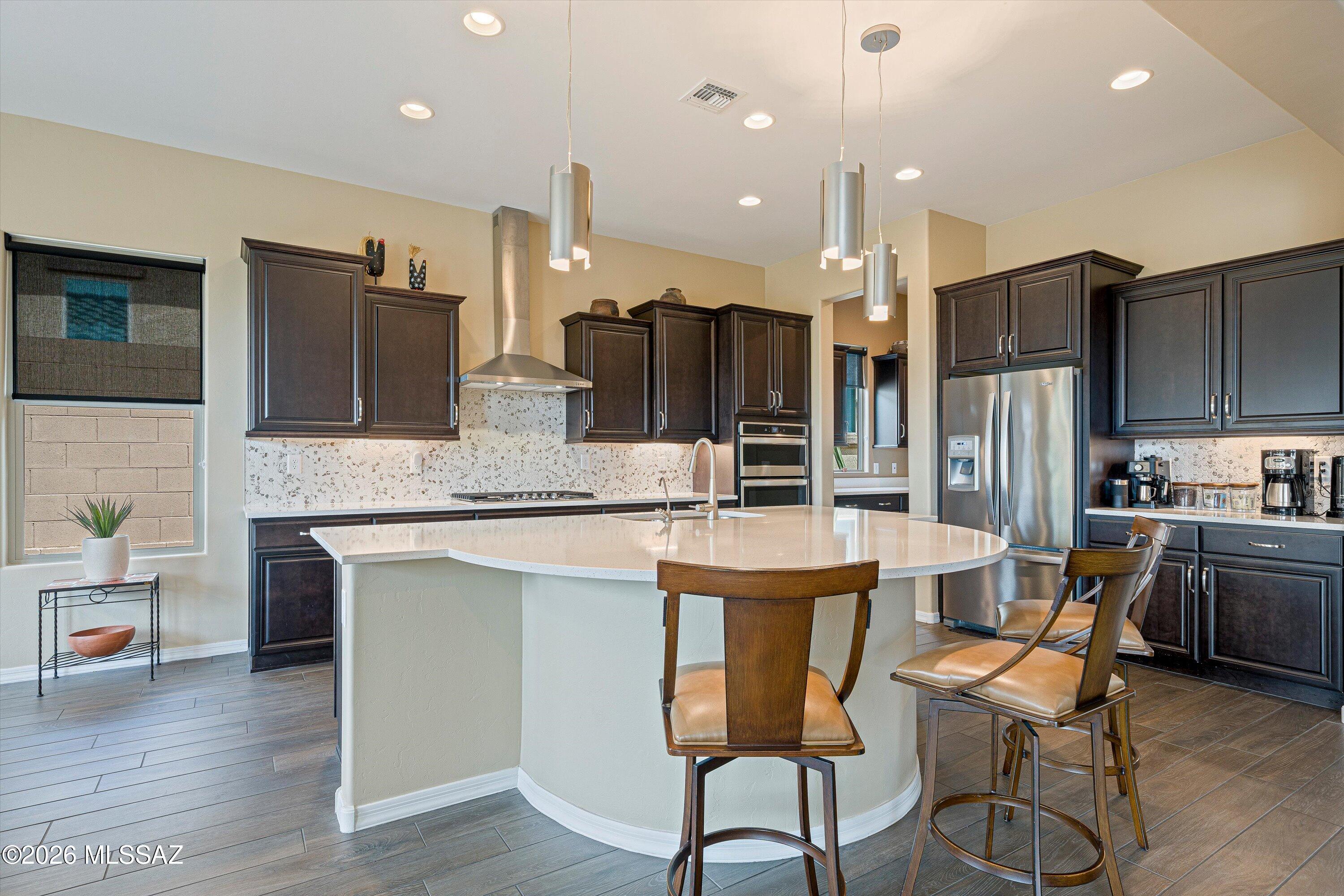 Motivated sellers welcome you to resort-style living in this beautifully appointed Journey model home nestled in the highly sought-after Del Webb at Dove Mountain community. Built in 2020, this stunning single-story showcases a classic Santa Fe-inspired exterior with a tile roof, charming courtyard with wrought iron gate, 2nd garage for a golf cart or storage, and thoughtfully planted desert landscaping that makes an unforgettable first impression -- especially at twilight.
Inside, the chef's kitchen impresses with rich dark cabinetry, quartz countertops, a gas cooktop, built-in wall oven and microwave, stainless appliances, and a tile backsplash. The open-concept layout flows seamlessly through the breakfast nook and into the main living areas, perfect for entertaining. The primary suite offers a private retreat with a well-appointed en-suite bath and walk-in closet. A dedicated office/den and a spacious second bedroom with its own full bath provide comfortable accommodations for guests. The dining room features a stylish bar area with a wine fridge -- ideal for entertaining in style. A convenient powder room rounds out the interior.
Both the front and back yards showcase owner-planted shrubs, trees, bushes, and cacti -- all serviced by a drip irrigation system -- creating a lush, curated desert landscape that's beautiful year-round.
Relax on the covered patio and take in stunning mountain views with gentle morning light and gorgeous afternoon sunsets -- all without the harsh glare of direct sun.
Del Webb at Dove Mountain residents enjoy world-class amenities: resort pool, fitness center, pickleball, tennis, and scenic walking paths -- all just minutes from Marana's dining, shopping, and golf.