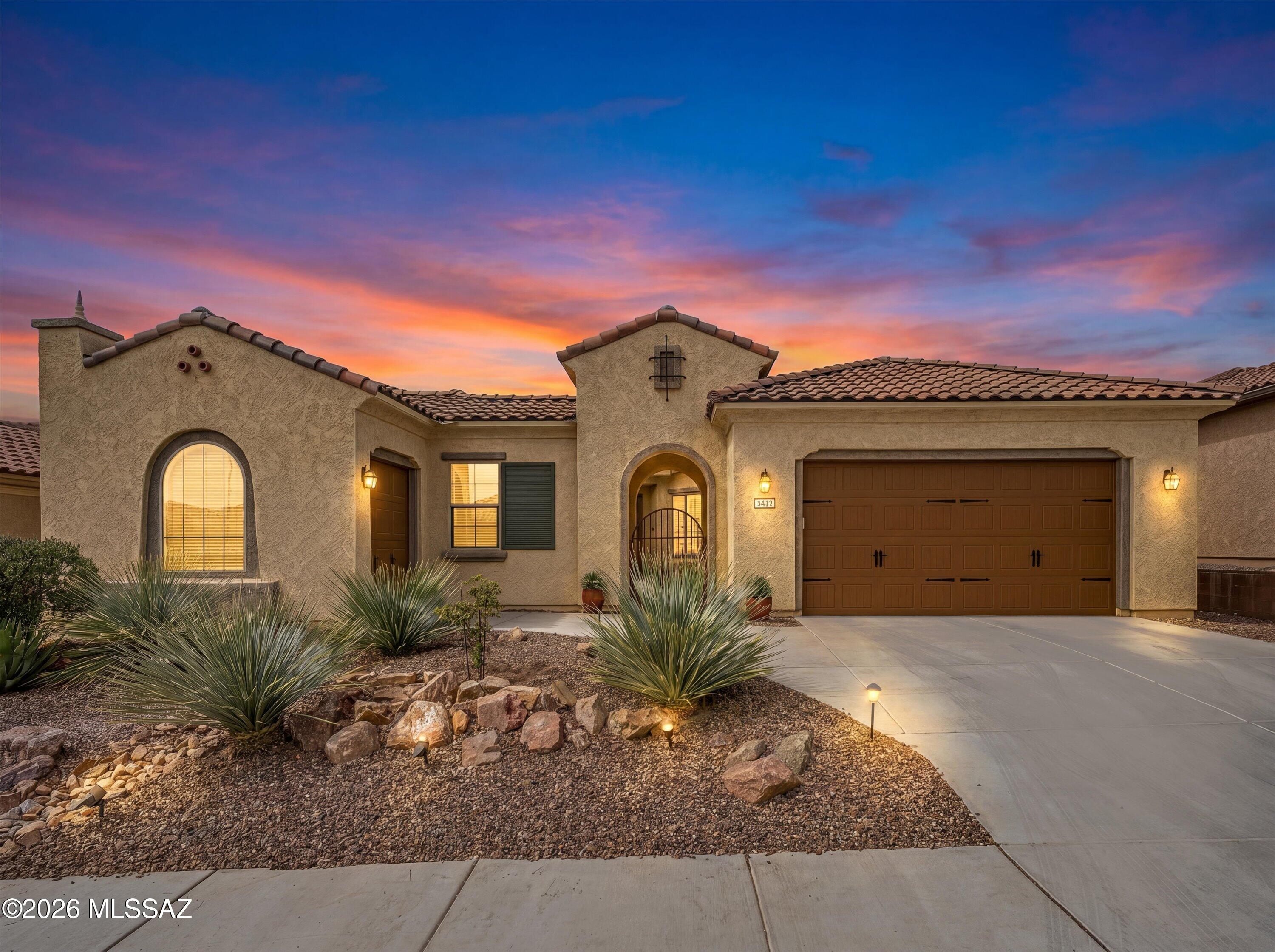Motivated sellers welcome you to resort-style living in this beautifully appointed Journey model home nestled in the highly sought-after Del Webb at Dove Mountain community. Built in 2020, this stunning single-story showcases a classic Santa Fe-inspired exterior with a tile roof, charming courtyard with wrought iron gate, 2nd garage for a golf cart or storage, and thoughtfully planted desert landscaping that makes an unforgettable first impression -- especially at twilight.
Inside, the chef's kitchen impresses with rich dark cabinetry, quartz countertops, a gas cooktop, built-in wall oven and microwave, stainless appliances, and a tile backsplash. The open-concept layout flows seamlessly through the breakfast nook and into the main living areas, perfect for entertaining. The primary suite offers a private retreat with a well-appointed en-suite bath and walk-in closet. A dedicated office/den and a spacious second bedroom with its own full bath provide comfortable accommodations for guests. The dining room features a stylish bar area with a wine fridge -- ideal for entertaining in style. A convenient powder room rounds out the interior.
Both the front and back yards showcase owner-planted shrubs, trees, bushes, and cacti -- all serviced by a drip irrigation system -- creating a lush, curated desert landscape that's beautiful year-round.
Relax on the covered patio and take in stunning mountain views with gentle morning light and gorgeous afternoon sunsets -- all without the harsh glare of direct sun.
Del Webb at Dove Mountain residents enjoy world-class amenities: resort pool, fitness center, pickleball, tennis, and scenic walking paths -- all just minutes from Marana's dining, shopping, and golf.