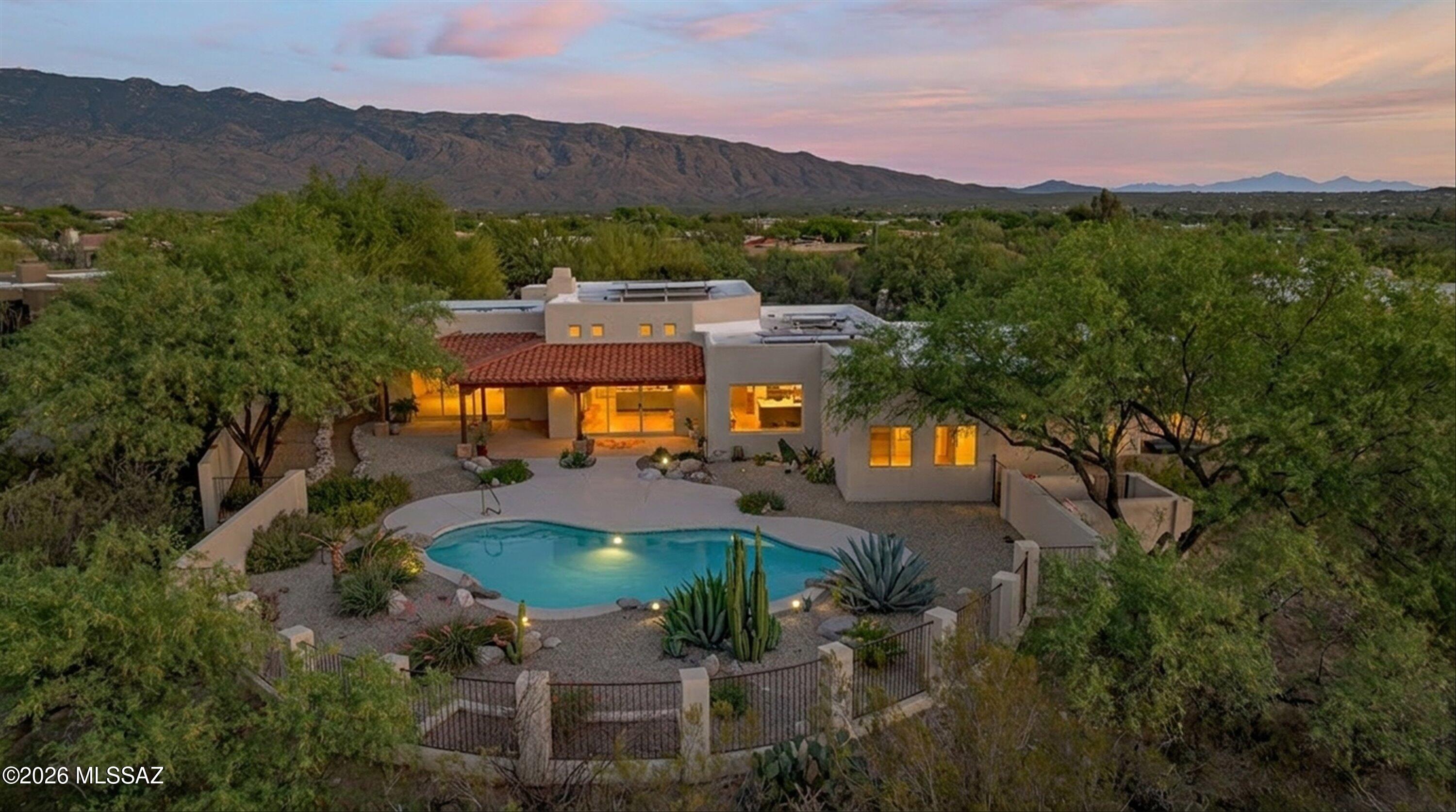 Warm and inviting, this Santa Fe-style residence is filled with rich character, soaring ceilings, and a thoughtfully designed split-bedroom floor plan. An oversized three-car garage with a dedicated storage room provides exceptional space for vehicles, hobbies, and organization, while the charming front courtyard welcomes you with a sense of privacy and serenity. Inside, every room captures views of the surrounding desert flora, seamlessly bringing natural beauty into everyday living.

The spacious great room serves as the heart of the home, highlighted by a wood-beam ceiling and an oversized custom-built-in cabinet designed for a large-screen TV, with an integrated display and storage.

The beautifully updated chef's kitchen showcases new cabinetry, stunning new countertops, Continued an induction cooktop, and an expansive island perfect for gathering, casual dining, and entertaining.

The private primary suite is a true retreat with its own gas fireplace, a generous walk-in closet, and views of the open desert and Catalina Mountains. Two additional bedrooms and a hall bath are positioned on the opposite side of the home for privacy and a well-equipped laundry room includes built-in counter space.

Designed for refined relaxation and effortless entertaining, the backyard features a pool and breathtaking views. The beautifully crafted tongue-and-groove covered patio creates an elegant, shaded outdoor living space perfect for year-round enjoyment.

Recent upgrades include a new roof, dual HVAC system, 24" x 48" tile flooring, remodeled kitchen with cabinet lighting, custom range hood, trash compactor, updated hall bath, water purification system, replastered pool, new pool pump, equipment, and owned solar for energy efficiency.

This exceptional home perfectly blends timeless Southwestern charm with modern comfort.