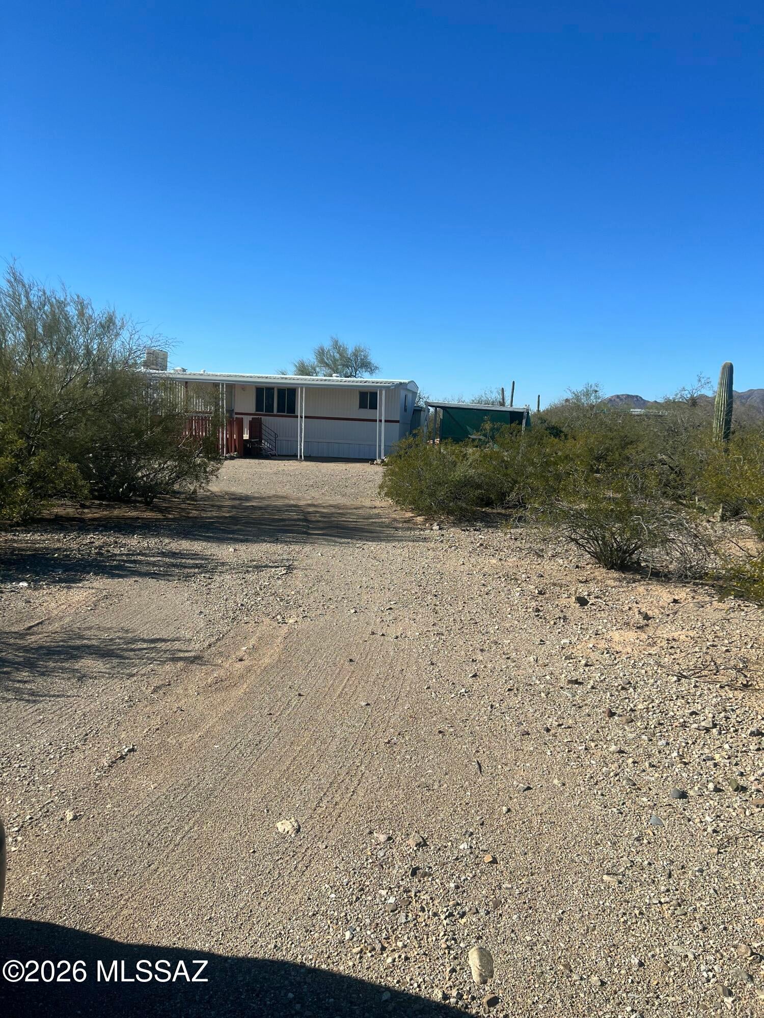 Peaceful desert setting. One flat acre with 2 bedroom, 1 & 1/2 bath home. All new paint, flooring, kitchen cabinetry & sink, evaporative cooler, and new vanity in 2nd bath and both have new toilets. Updated electric. Two large awnings were converted into living space, not assessed in county records. Shed has hookup and washing machine. Beautiful mountain, sunrise, and sunset views. Fully fenced on three sides with wash bordering unfenced north edge of property. Gated entry with circular driveway. Space for many uses. Clean and move in ready!