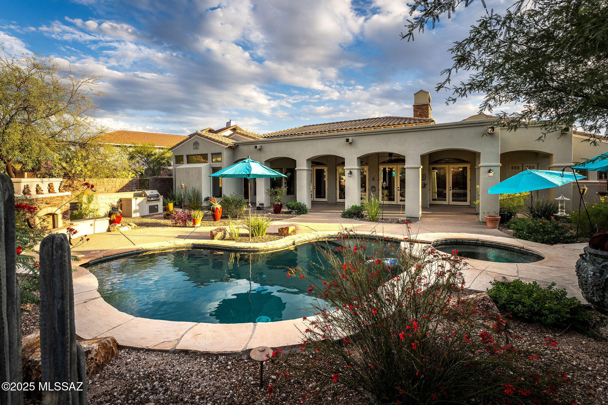 Experience luxury living in this stunning custom Catalina Foothills home, perfectly situated in a private gated community with breathtaking mountain and city views. Built in 2009, this 3,700+ sq. ft. residence showcases exceptional craftsmanship and thoughtful design throughout. The gourmet kitchen is a chef's dream, featuring dual islands, custom cabinetry, striking granite countertops, a pot-filler, walk-in pantry, and premium stainless steel appliances. The spacious open-concept living and dining areas boast 14-foot ceilings, crown molding, elegant lighting, a fireplace with custom built-ins, and triple French doors that open to a beautiful covered patio—creating the perfect setting for entertaining or relaxing. The luxurious primary suite offers 10-foot coffered ceilings, serene city light views, and a spa-inspired bath with dual vanities, a soaking tub, oversized shower, and a custom walk-in closet. Two additional bedrooms each feature walk-in closets and private ensuite baths, providing comfort and privacy for family and guests. A separate den with built-in cabinetry and a queen-size Murphy bed adds flexibility for an office or occasional 4th bedroom, while a bonus room with patio access is ideal for a fitness area, media room, or creative studio. Step outside to enjoy true resort-style living in the backyard, complete with a sparkling Pebble Tec pool, raised spa with cascading waterfall, outdoor fireplace, built-in BBQ, and covered patio perfect for gatherings, all surrounded by sweeping mountain views. Additional features include a three-car garage with storage, dual high-efficiency HVAC systems, a water treatment system, and dual tankless water heaters. Located just minutes from upscale shopping, dining, golf, hiking, and top-rated schools, this home offers the very best of the Foothills lifestyle.