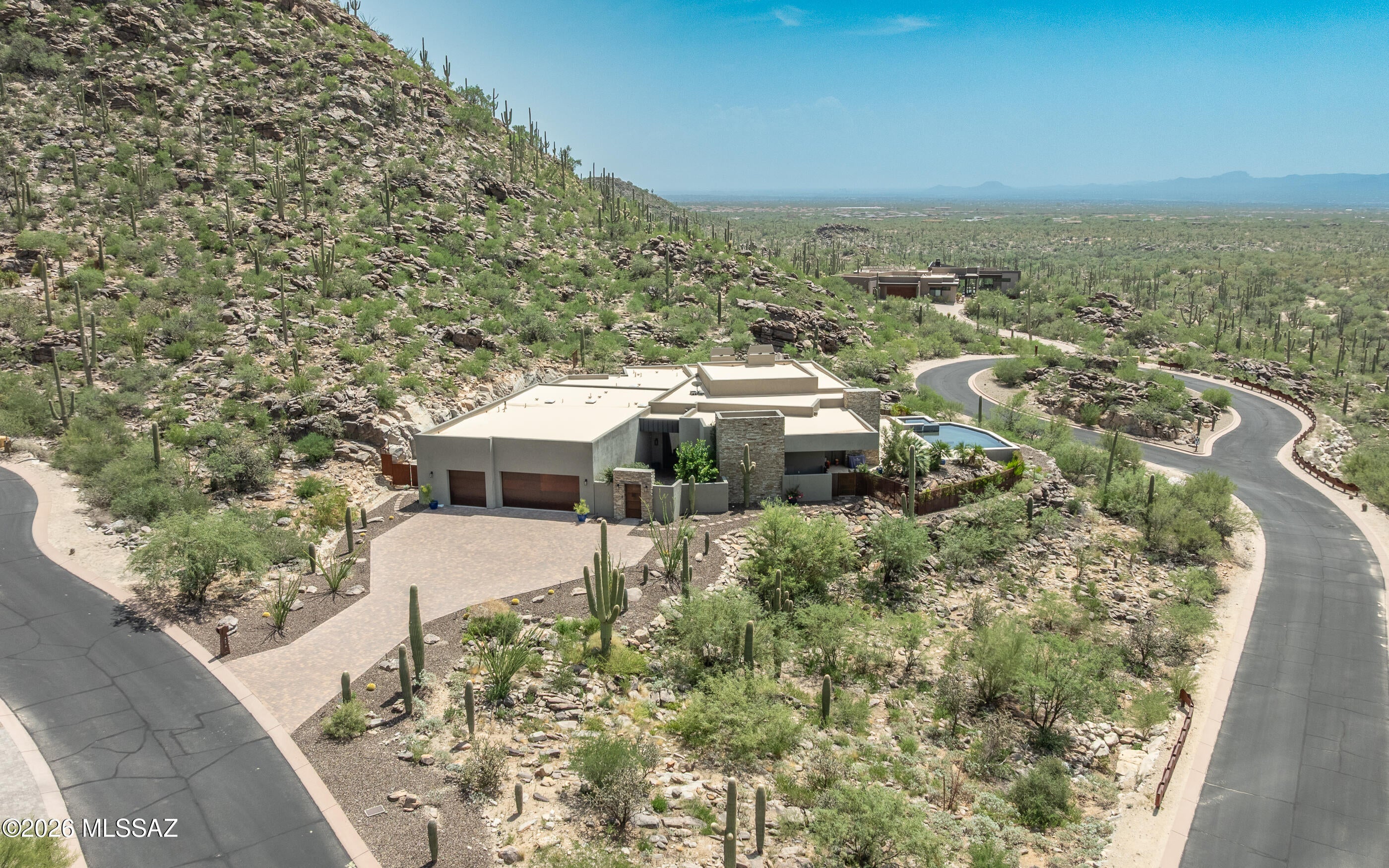 Endless panoramic views from almost all windows! This modern contemporary open great room custom masterpiece is an ideal entertainers home w/spacious gourmet kitchen open to dining and the the massive great room that hosts a glass wall chilled wine room, linear fireplace, one of the largest of TV walls. The finishes are beautiful from the leather black granite kitchen countertops, travertine floors, modern styled cabinets throughout the home. There are walls and walls of windows that all boast gorgeous views, including some of the most mesmerizing sunsets.  Very private location against a mountainside cul-de-sac location of the southern end of Canyon Pass at Dove Mountain. Did I mention the 6 car tandem garage w/extra storage rooms, electric vehicle charger and simple flat easy driveway. Other outstanding features are electronic shades on all large view windows, all bedrooms are en-suites. Fabulous laundry room w/more than abundant storage cabinets. The largest of the bedrooms is set up as an art studio- entertainment room, with TV wall and shelving unit and private walk-out patio w/gorgeous views. So many uses for this room:  media room, huge den/office, craft room, music room, huge exercise room, it's just plain large!   Sellers have added additional fencing around the entire SE side of home - great for creating a private garden, citrus tree grove or a private space for dogs or to rest and play privately.  Beautiful sleep pool and spa along with very large patio firepit near the outdoor under porch TV station for night time movie watching or sports gatherings.  Again - a great entertainers home - everything is large and open or just a private oasis retreat for yourself and family.