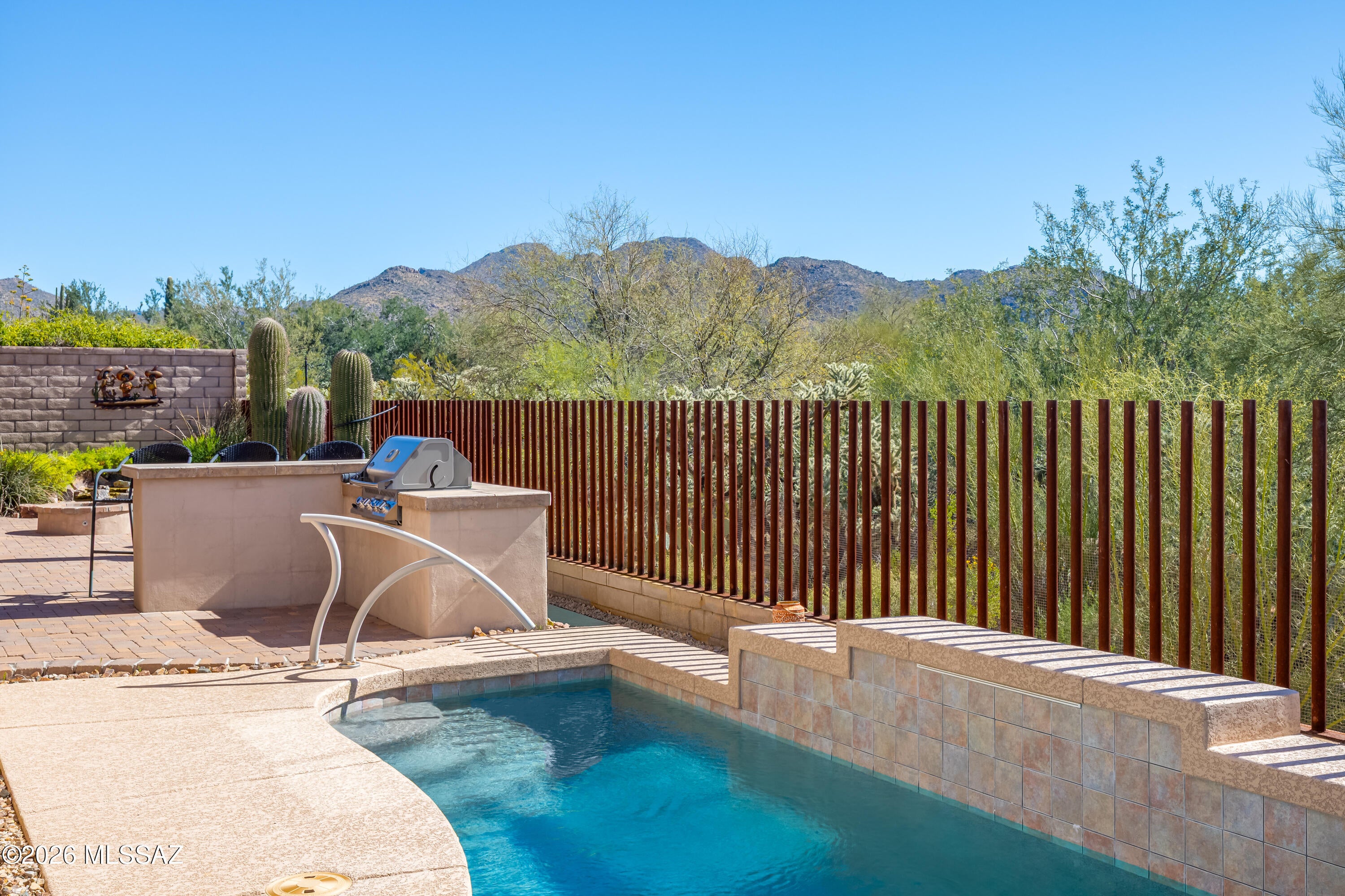 Perched on the 10th fairway of the Gallery Golf South Course  this home is perfectly situated for sunrise views. Located in the desirable Los Saguaros community of Dove Mountain this spacious residence features 3 bedrooms plus a dedicated office/den and a 3-car tandem garage. The thoughtfully designed open floor plan showcases tile flooring throughout the main living areas with comfortable carpet in the bedrooms, creating both durability and warmth where it matters most.
The well-appointed kitchen is perfect for everyday living and entertaining, featuring double ovens, a cooktop, a natural stone island, and abundant cabinetry with soft-close doors and drawers, along with glass-front cabinet doors.  The plunge pool is perfect for gatherings on the patio!