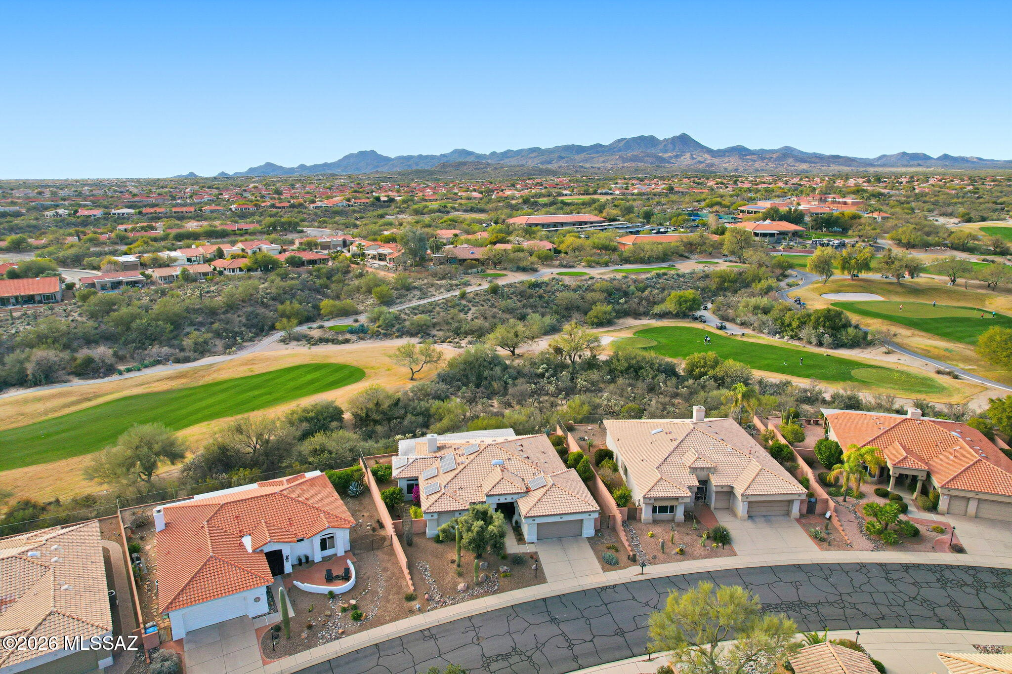 Extended Mountainview floor plan with 2,186 sq ft featuring two private suites, a den, and a half bath off the kitchen. Completely updated and elevated above the Sun City Oro Valley golf course with breathtaking mountain and sunset views from both front and back patios. Outdoor living includes a pergola with drop-down sunscreens for year-round comfort. A double-sided gas fireplace adds warmth and ambiance. The updated kitchen offers shaker cabinets, KitchenAid gas range, marble backsplash, and opens to an extended sitting area with views. New Summit Series stone composite flooring throughout. Remodeled baths with quartzite counters, new vanities, and a marble shower in the primary suite. Hunter Douglas window coverings and shutters. Replaced roof underlayment, owned solar, and HVAC (2020)