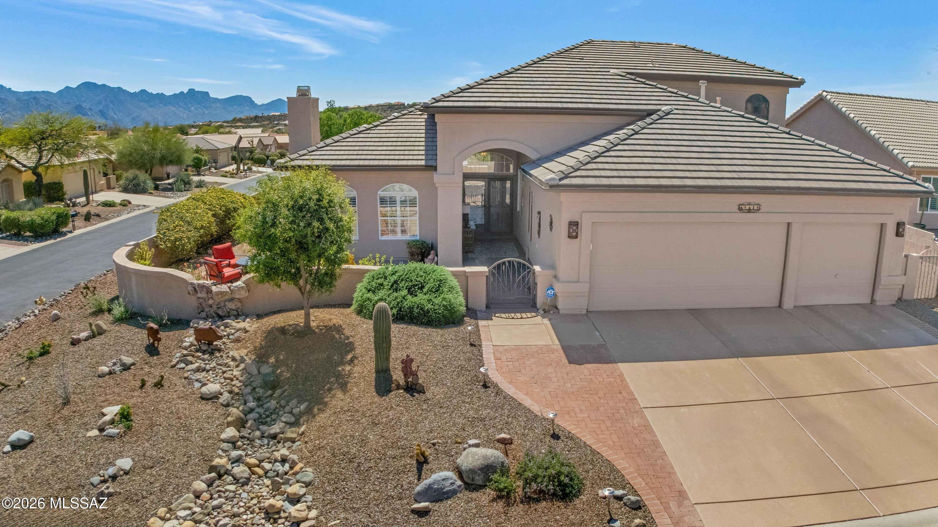 Beautifully Updated Galleria in SaddleBrooke on an elevated corner lot with mountain views! Inviting front gated paver courtyard leads to glass entry doors & grand double-door entrance. Foyer opens to living room with stacked stone fireplace & dining area with solar tube, plus wet bar station with wine cooler. Family room opens to kitchen with patio access. Kitchen features granite countertops, stainless steel appliances, gas cooktop, double ovens, walk-in pantry & kitchen dining. Den/Office & powder room. Owner's suite has patio access & ensuite with dual vanity, granite counters, tiled walk-in shower, soaking tub, & 2 walk-in closets. Upstairs, 2 guest bedrooms with closets & guest bathroom with walk-in shower. Laundry room has W/D & cabinets. 3 car garage with sink & cabinets. Enjoy outdoor living with covered paver patio & 2 electric rolling shades. Extended paver patio with fireplace, hot tub, built-in BBQ station, 6 fruit trees, lovely landscaping, nature behind & gated yard--all with mountain views!