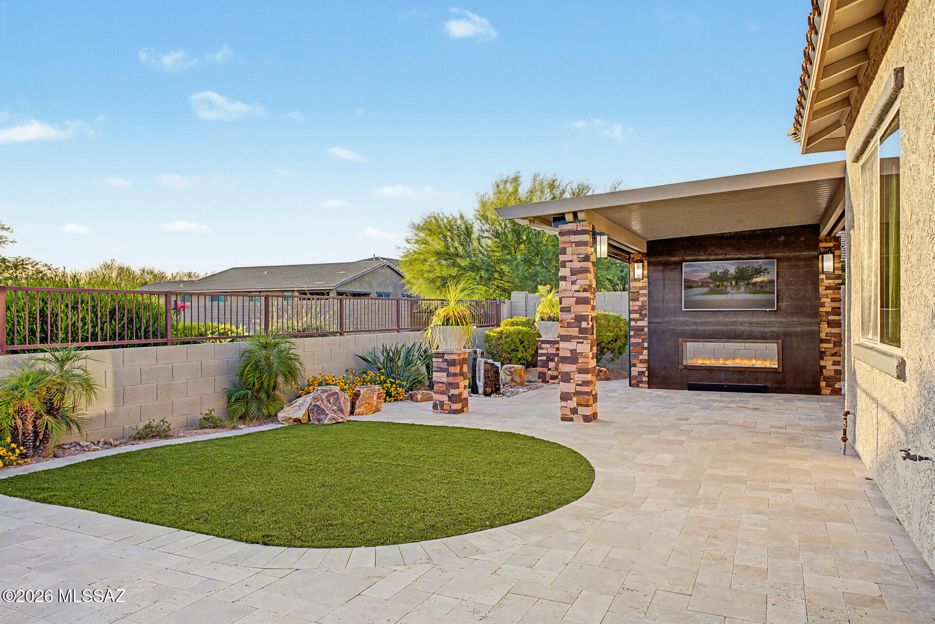 Beautiful Oro Valley home, meticulously maintained, single story with 3,045 sq ft. Professionally designed landscaping features a pool, water features front and back, outdoor lighting, travertine pavers, entertainer's backyard with large covered patio, roller shade, custom fabricated metal gas fireplace with mounted TV and a spacious outdoor kitchen with granite counters. This 4 bedroom, 2-1/2 bath home includes a teen room/den, fresh interior and exterior paint and updated lighting. Large kitchen with gas cooktop, kitchen island, office nook, sliding glass wall system that opens seamlessly to the backyard and a unique roll-up garage pass-through door to the backyard kitchen. Tandem 3-car garage with finished floor. Ideal for Tucson living, close to schools, shopping, and dining