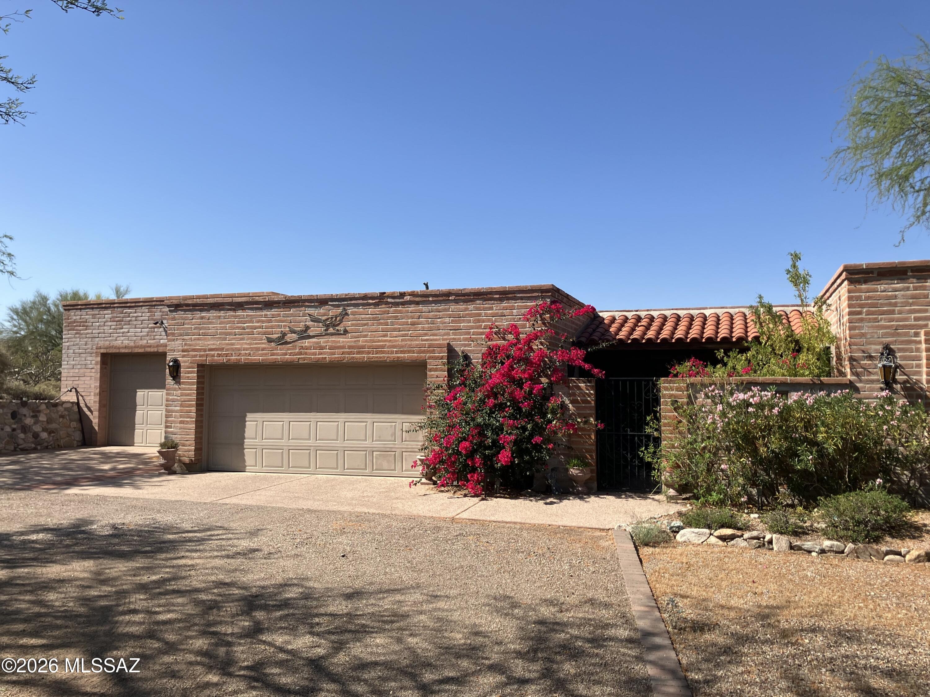Lovely adobe home with views on quiet cul-de-sac on over an acre in Catalina Foothills! Two garages accommodate up to 4 vehicles, with workshop and loads of built-in storage. The gated courtyard with buzzed entry provides a secure buffer. The house also has an abundance of storage and includes a custom office closet with desk, a bay window seat with cedar chest, and a murphy bed. The dining area overlooks the living room fireplace and has French doors to a covered deck - perfect for your morning coffee, The covered patio with access from living room and bedroom offers beautiful sunset views. The circular driveway provides generous parking. Two HVAC units plus evap cooling in garage to keep you comfortable!